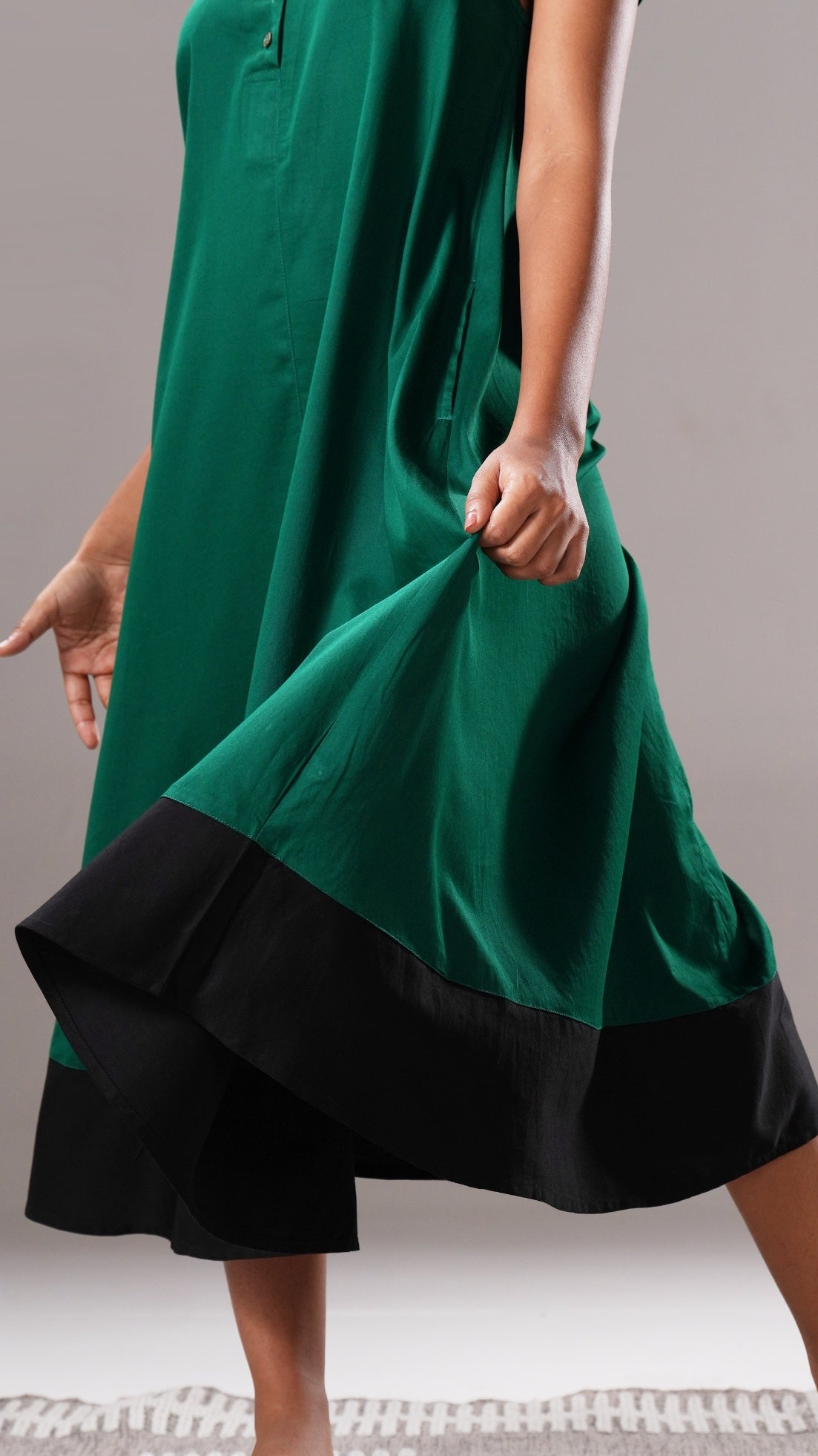 Green dress with black hem on a neutral background