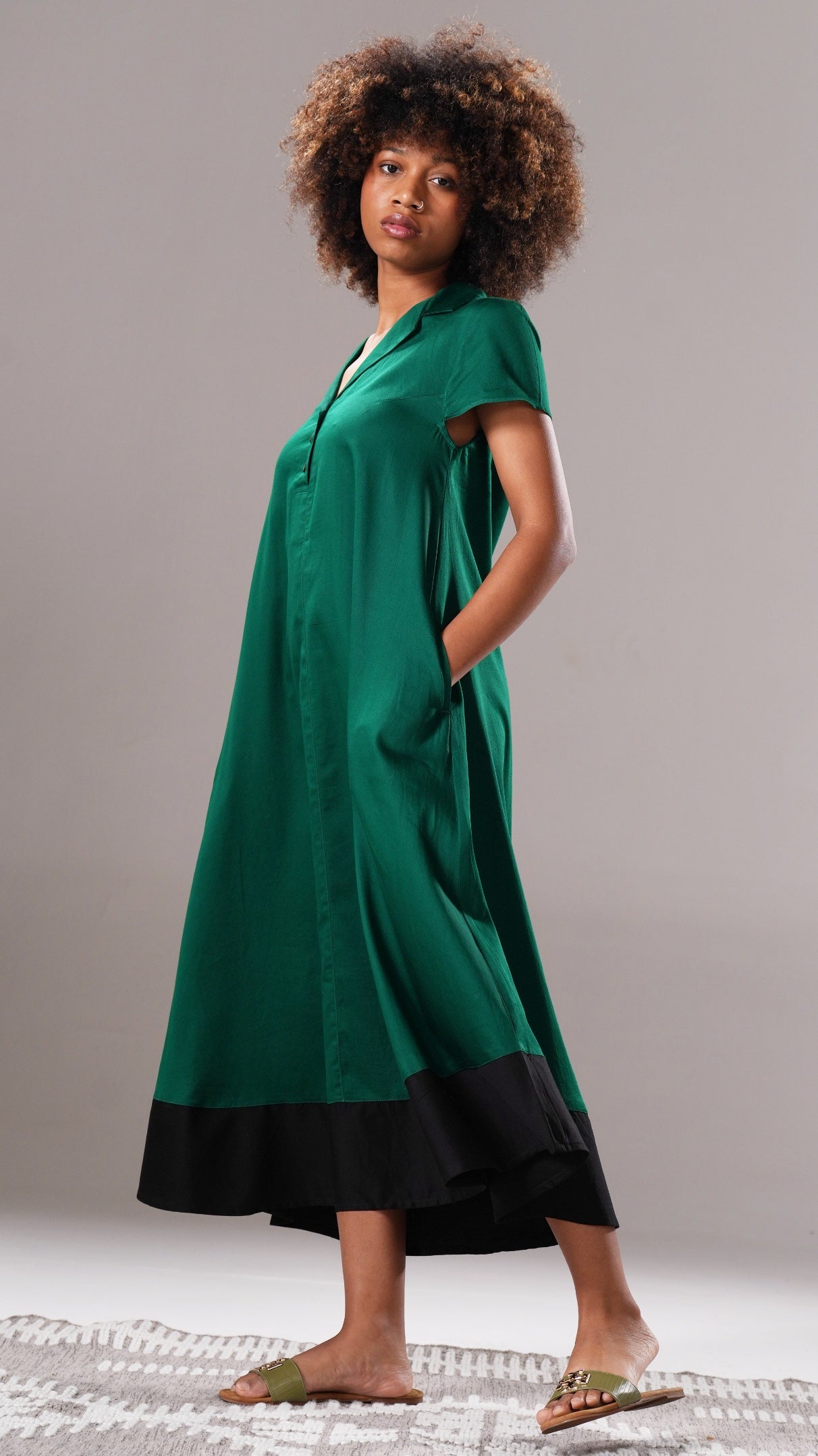 Woman wearing a green dress with a black bottom section on a neutral background