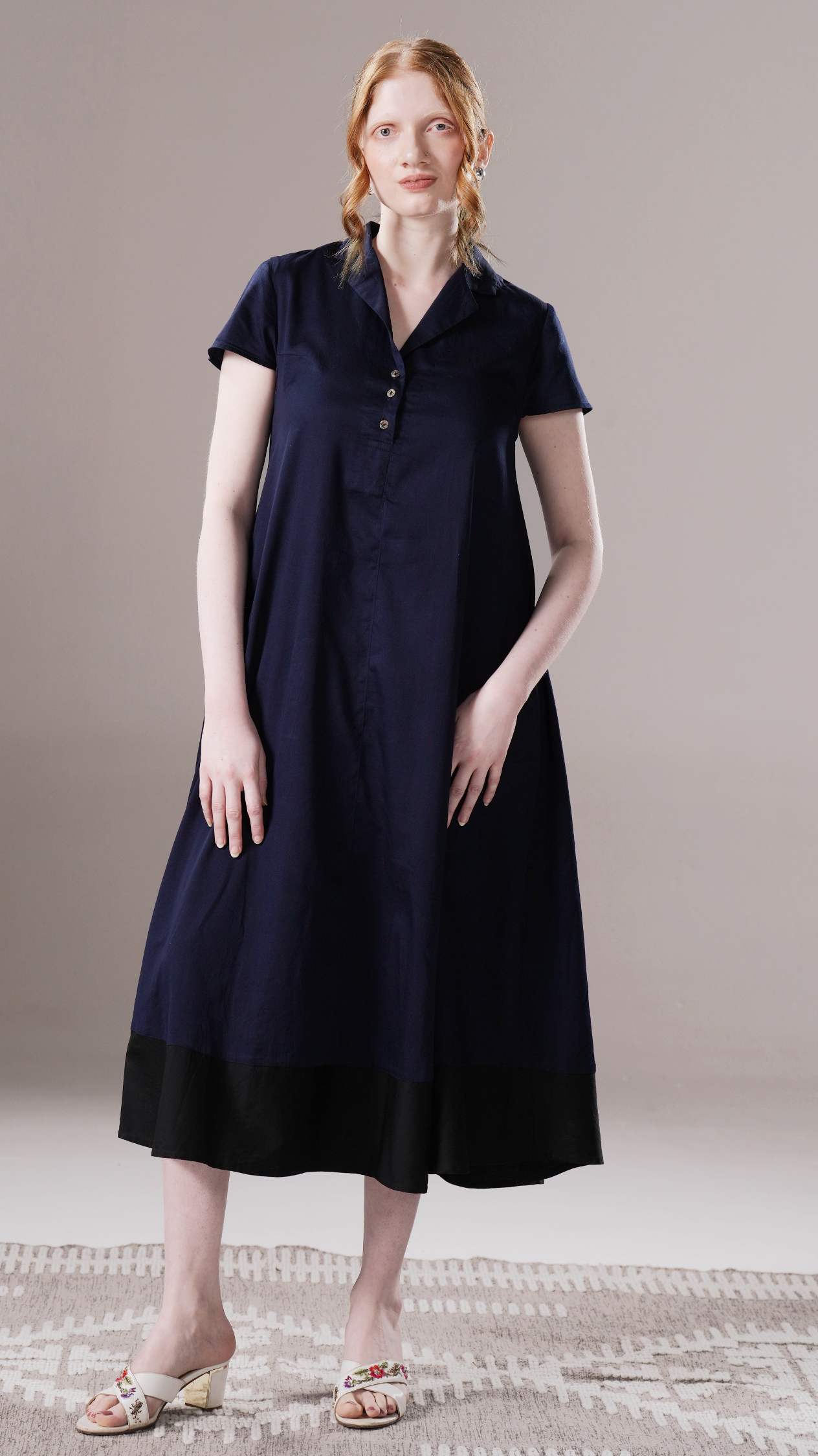 Woman wearing a navy blue dress with a plain background