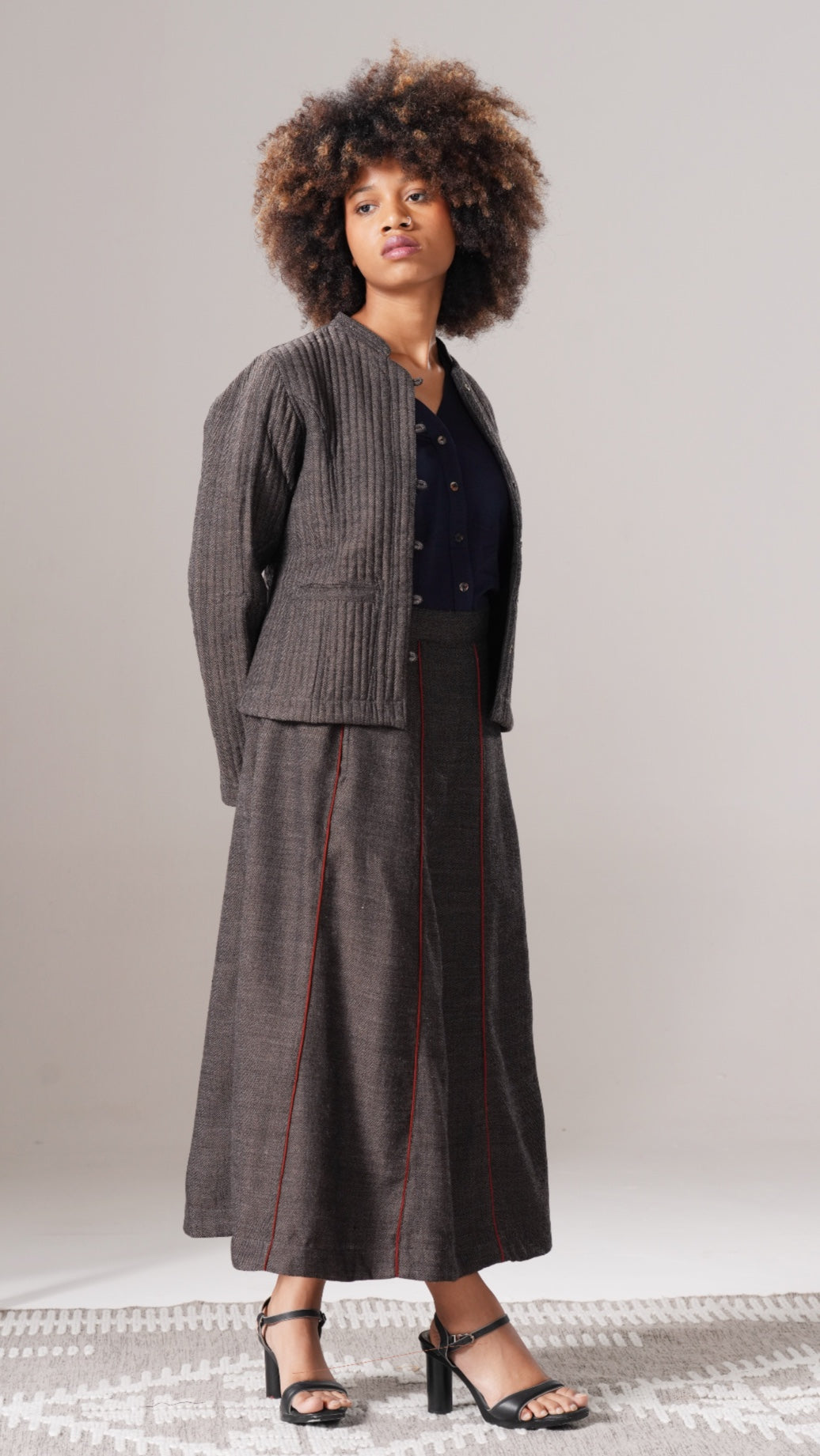 Woman wearing a gray checkered suit with a black top against a plain background