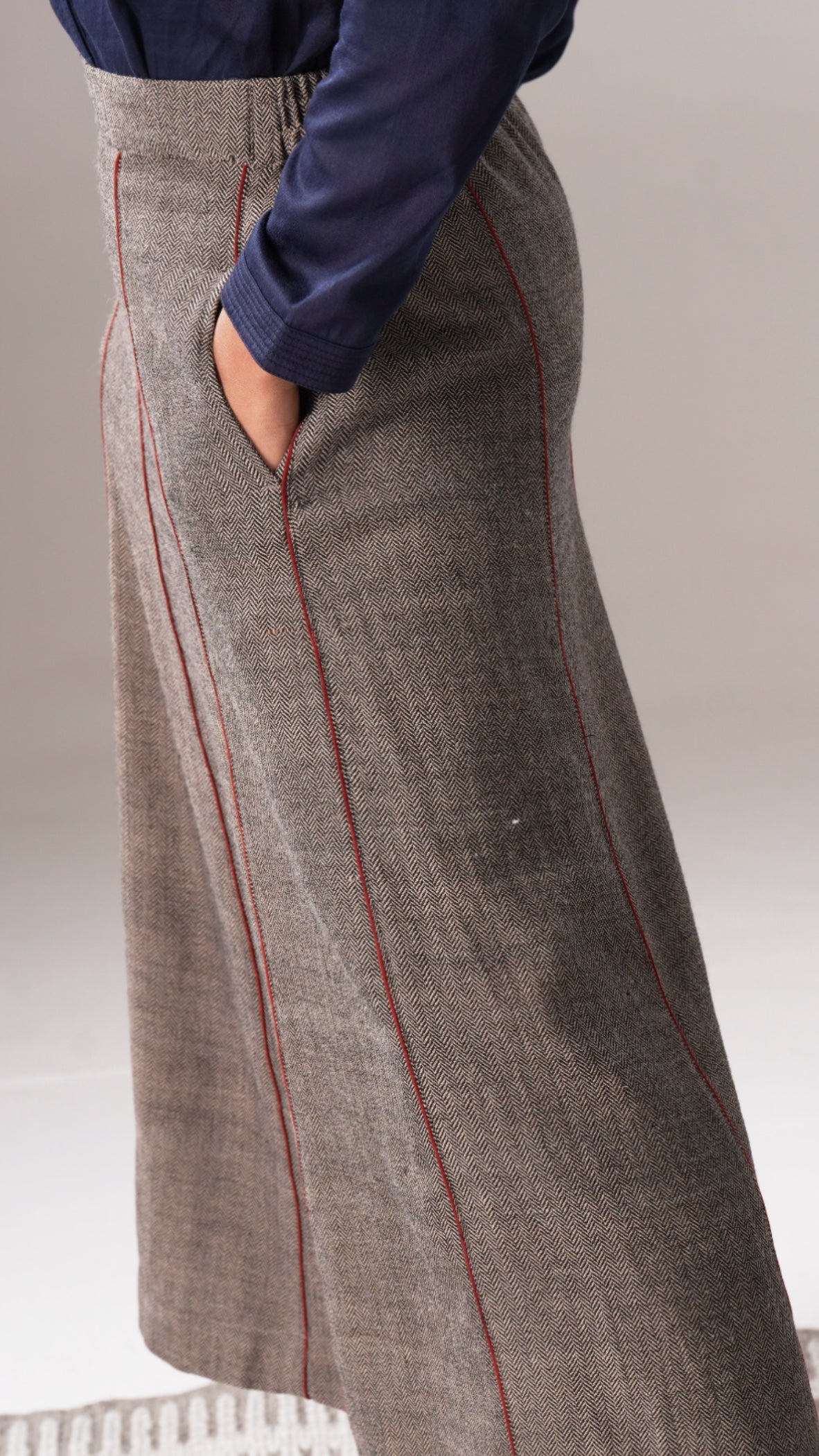 Long brown skirt with red stitching worn by a person on a neutral background