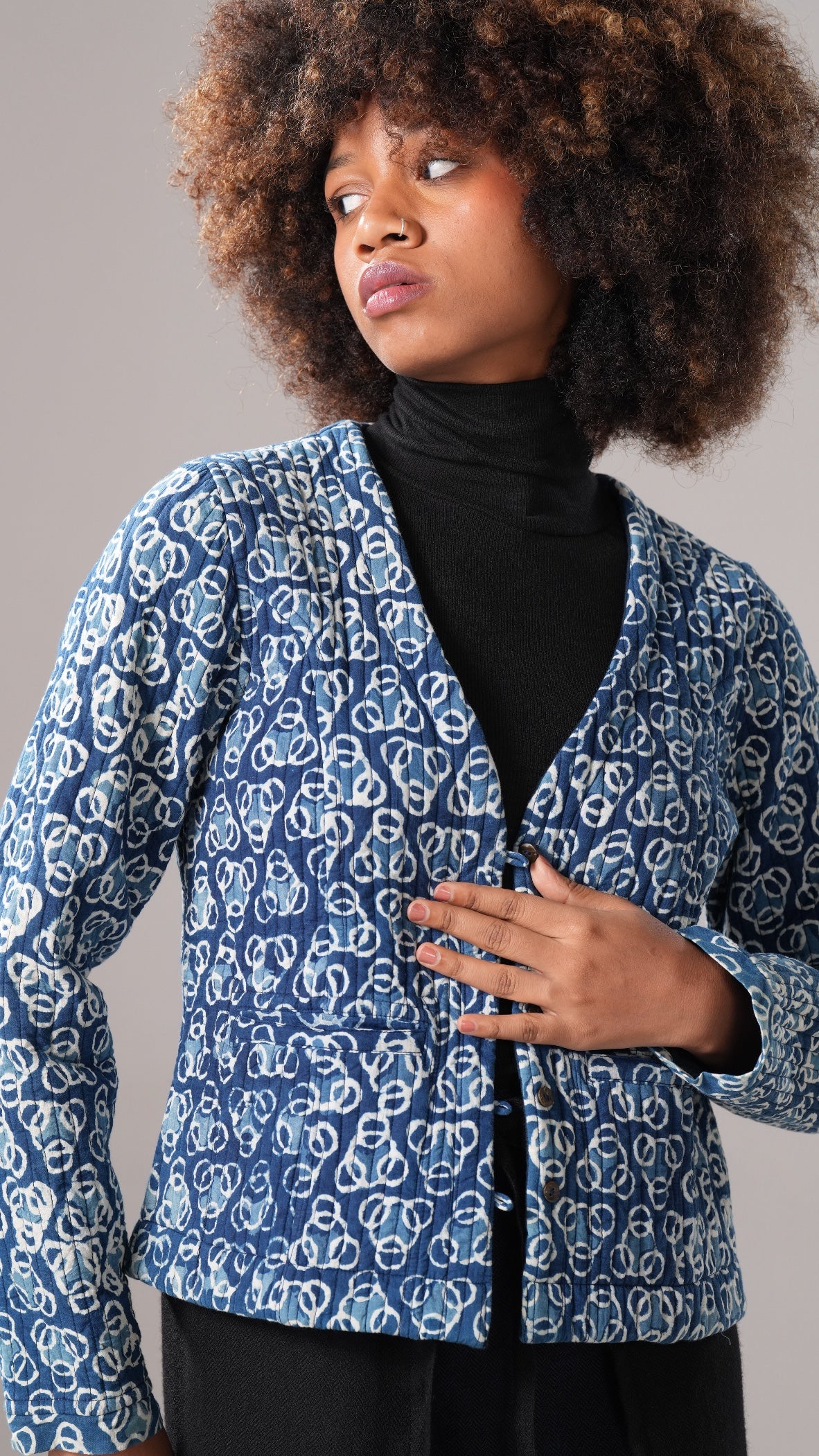 Woman wearing a blue patterned jacket against a gray background