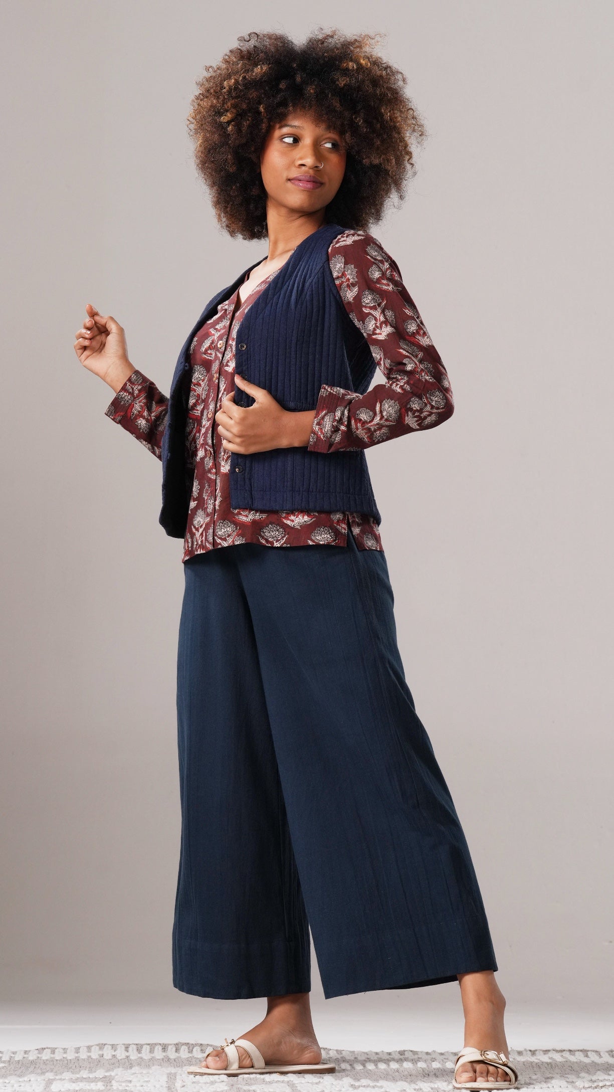 Woman wearing a navy outfit with a patterned cardigan against a plain background