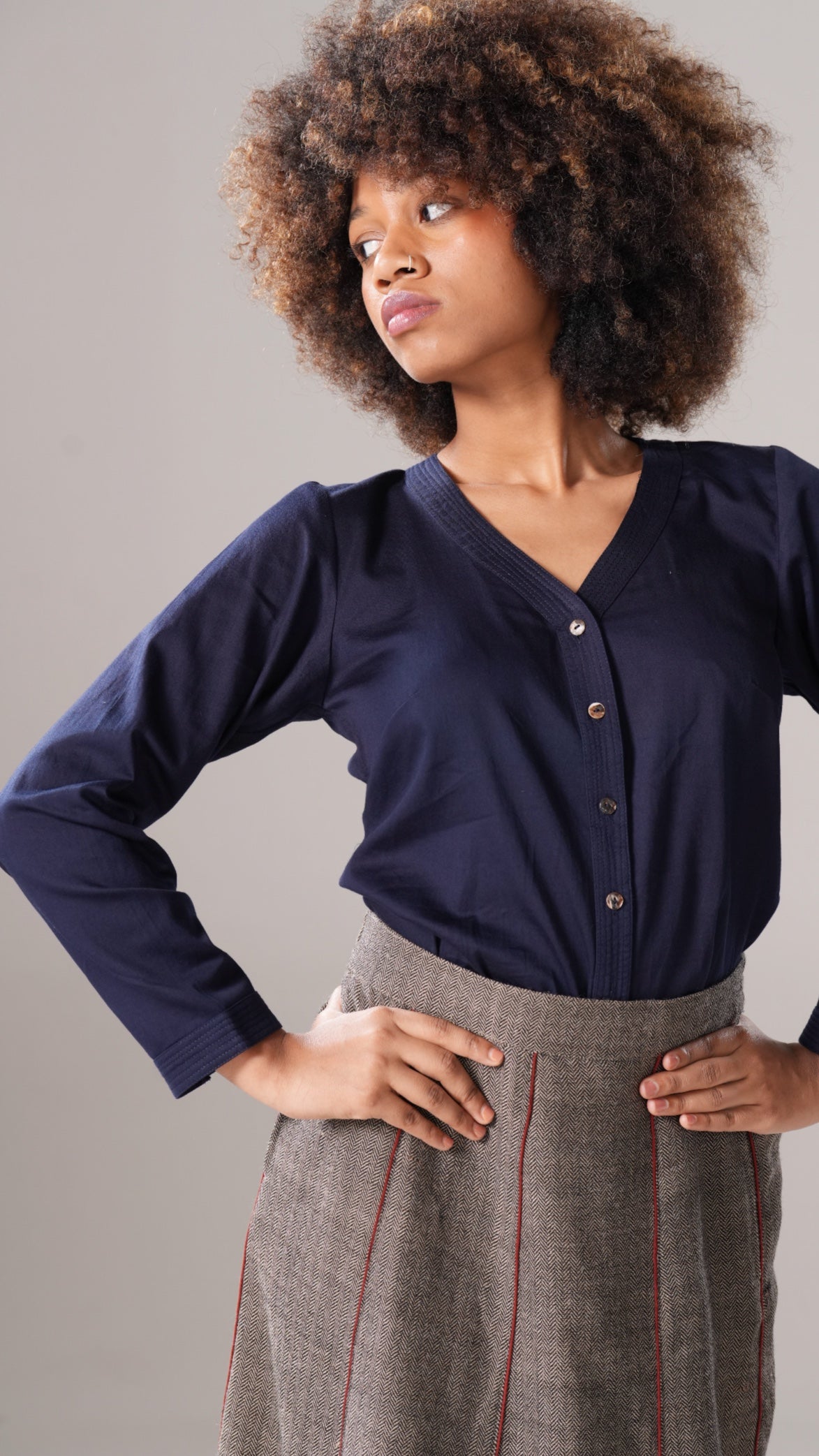 Woman wearing a navy blue blouse and gray skirt against a plain background