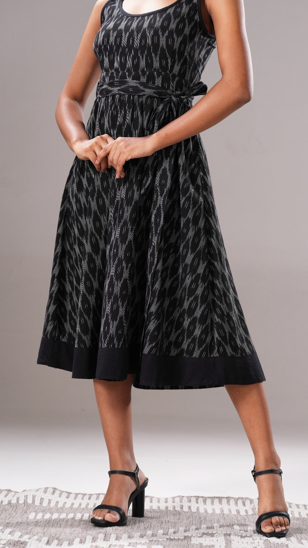 Woman wearing a black patterned dress on a neutral background