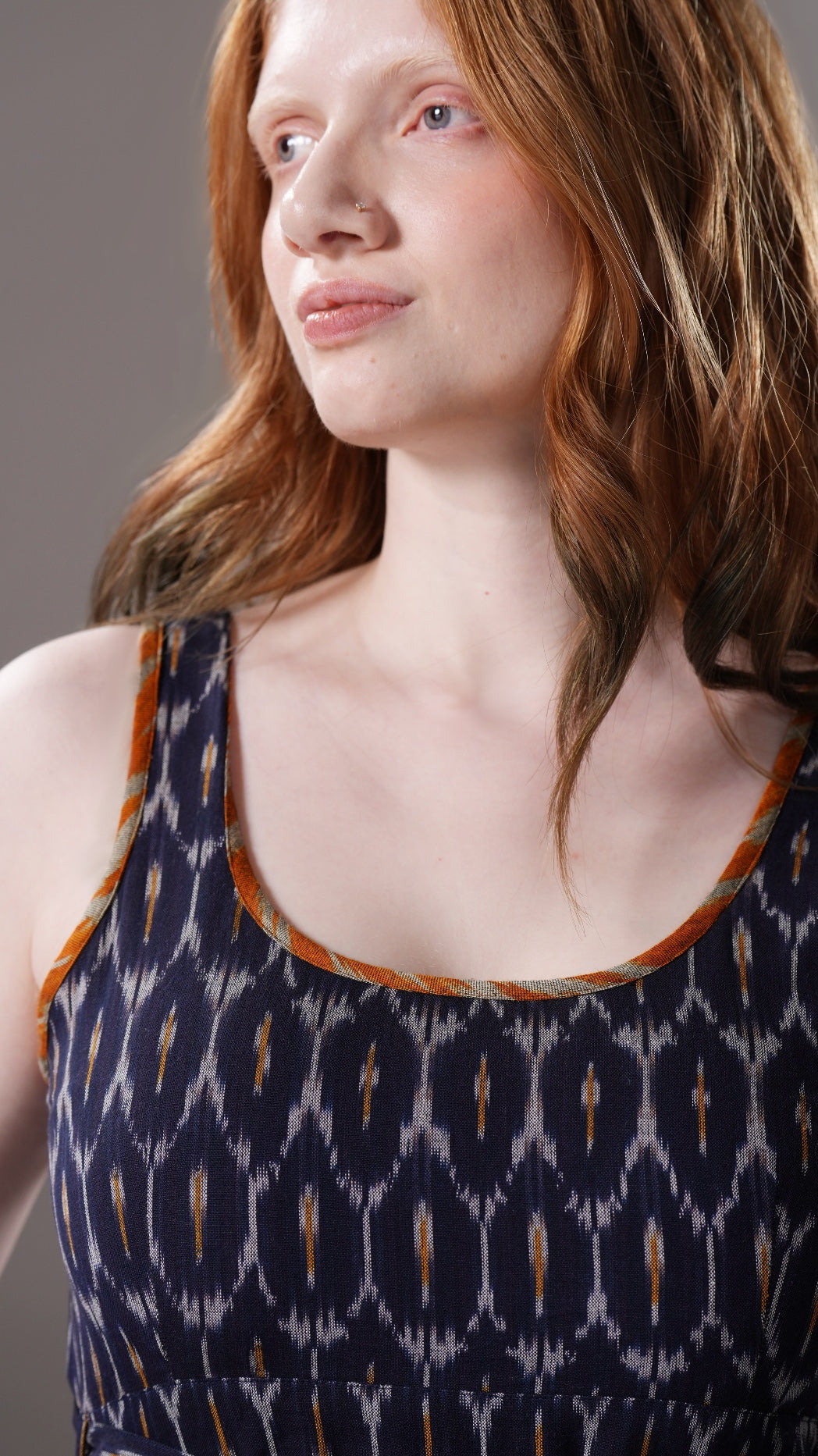 Woman wearing a sleeveless dress with a geometric pattern on a plain background