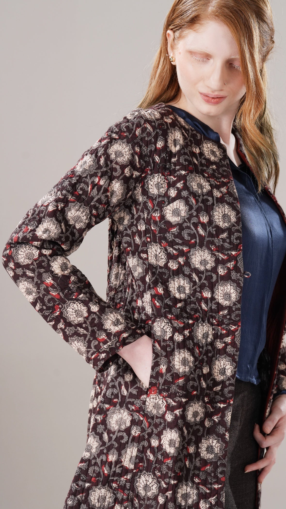 Woman wearing a floral patterned coat against a gray background