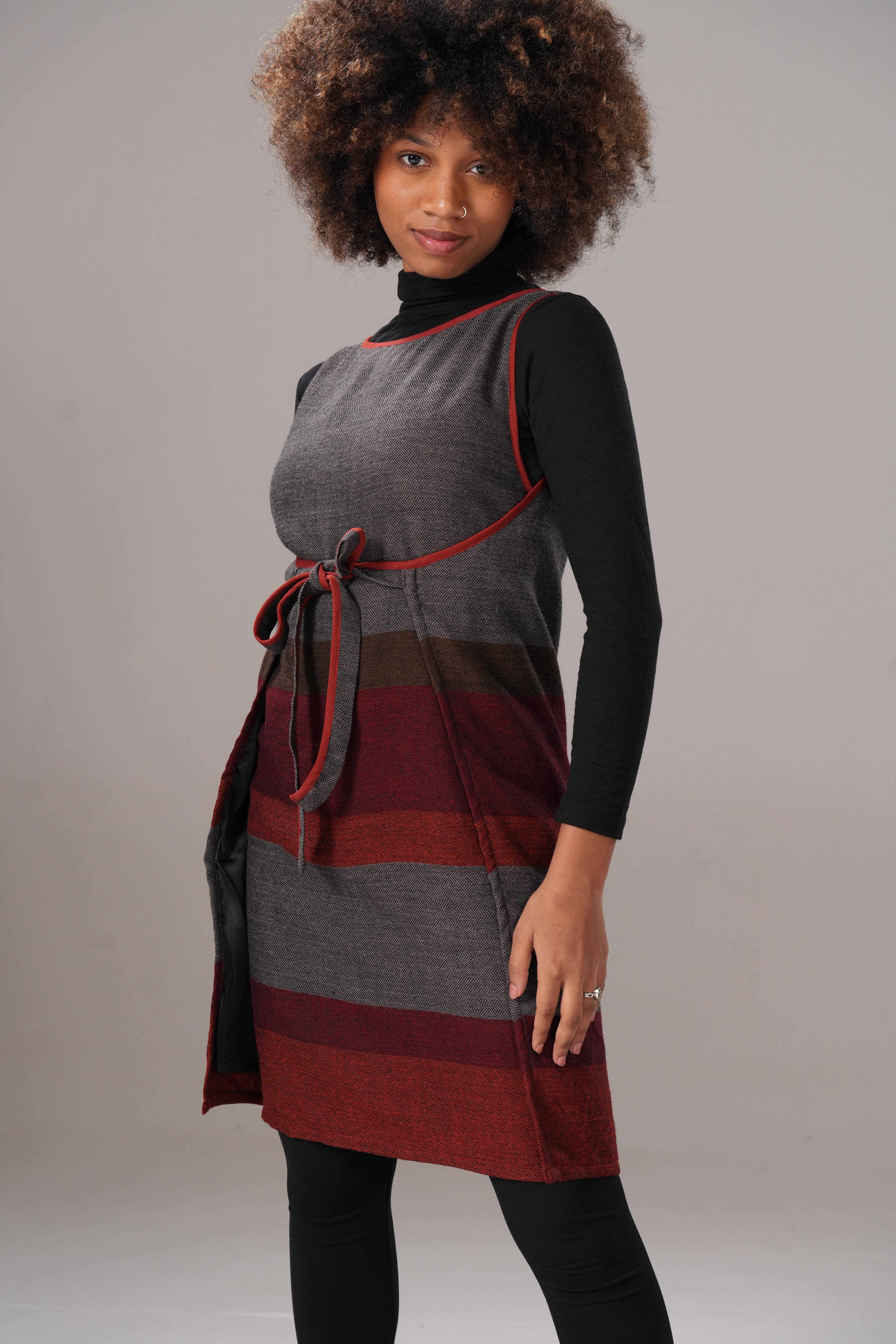 Person wearing a gray and red dress with a plain background