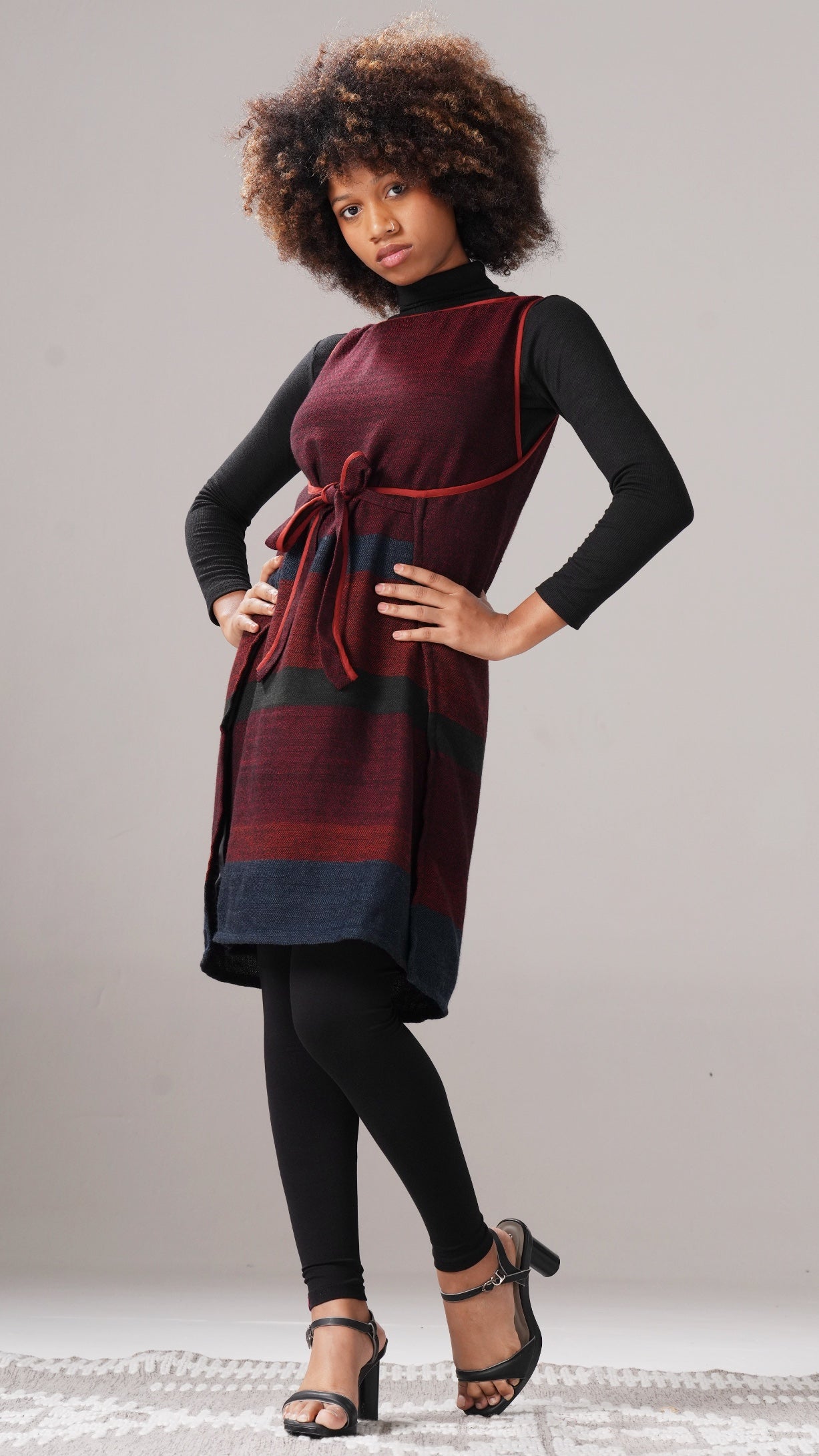 Woman wearing a maroon and black dress with a plaid pattern on a gray background