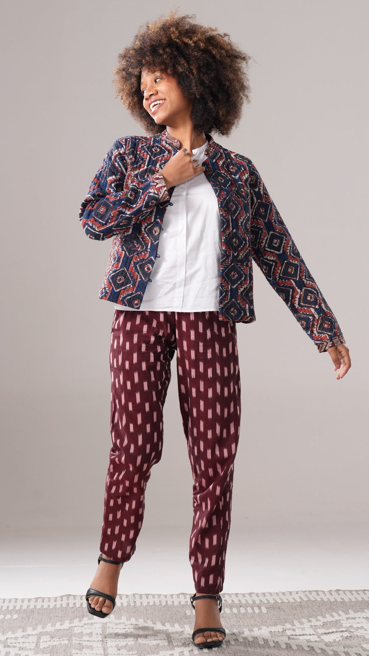 Woman wearing a patterned jacket and pants on a plain background