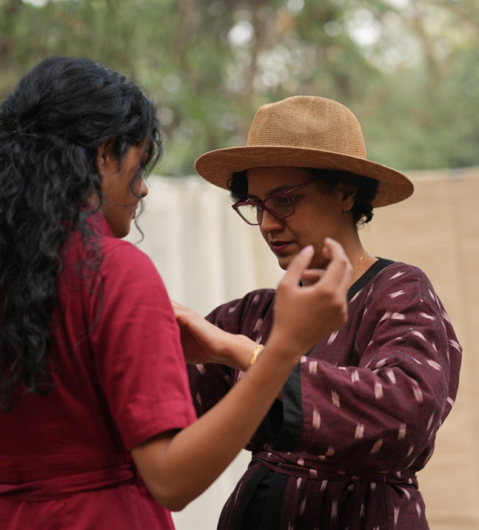 Two women interacting outdoors with a blurred natural background