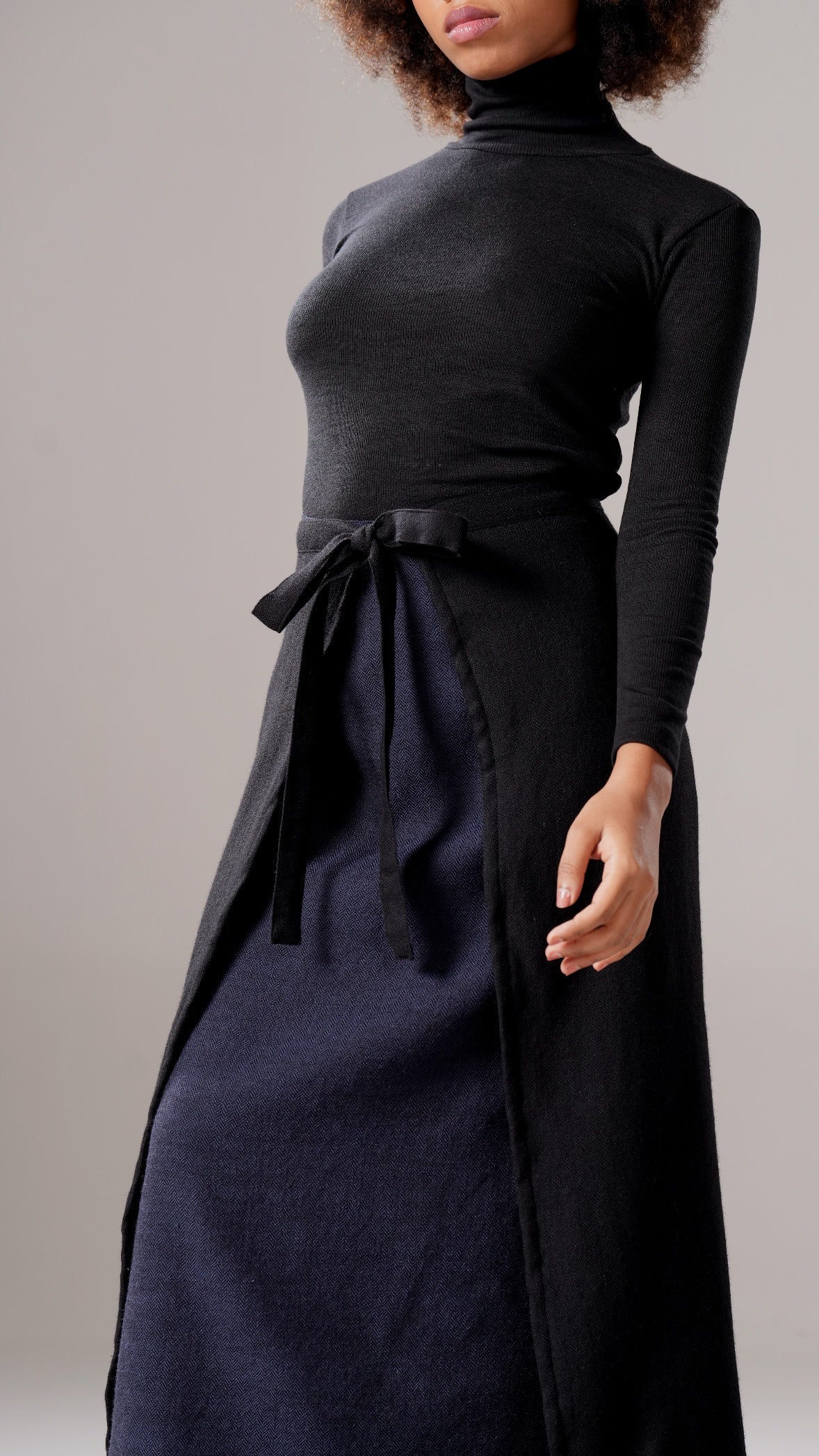 Person wearing a black turtleneck and navy apron against a plain background