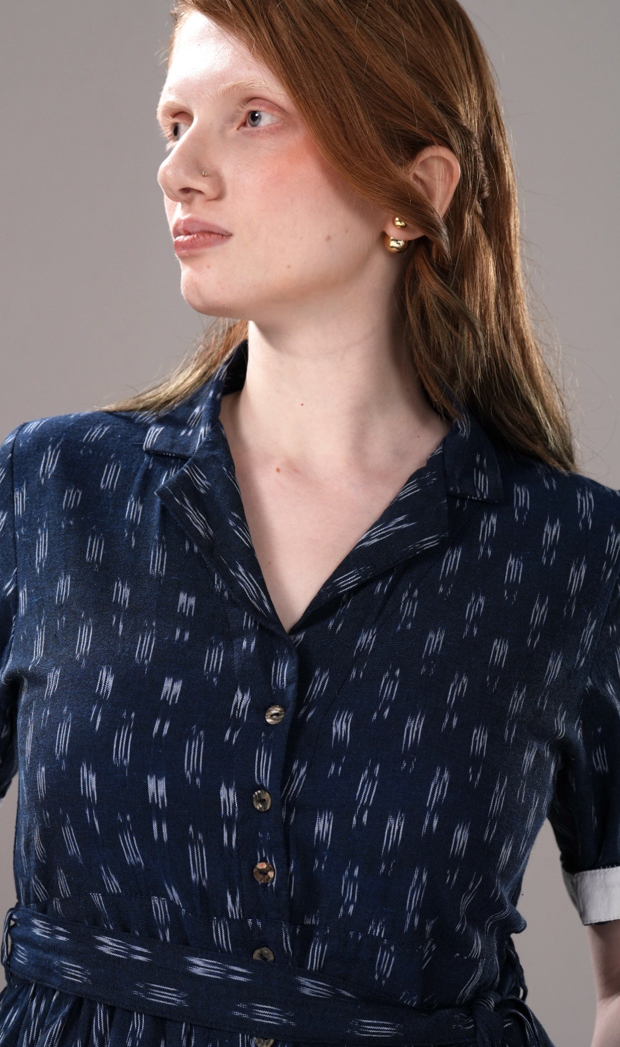 Woman wearing a navy blue dress with white pattern against a gray background