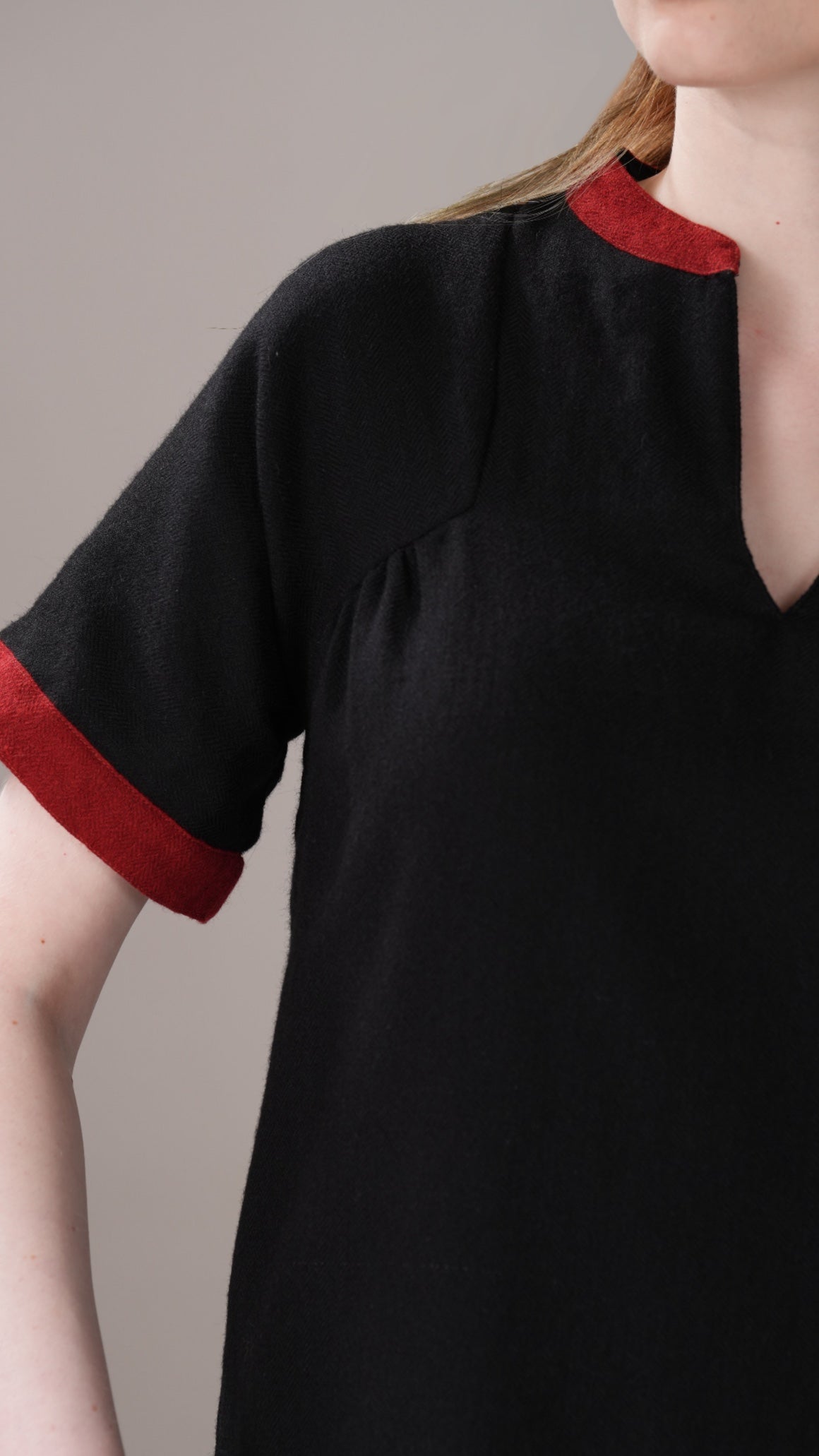 Black dress with red trim on a neutral background