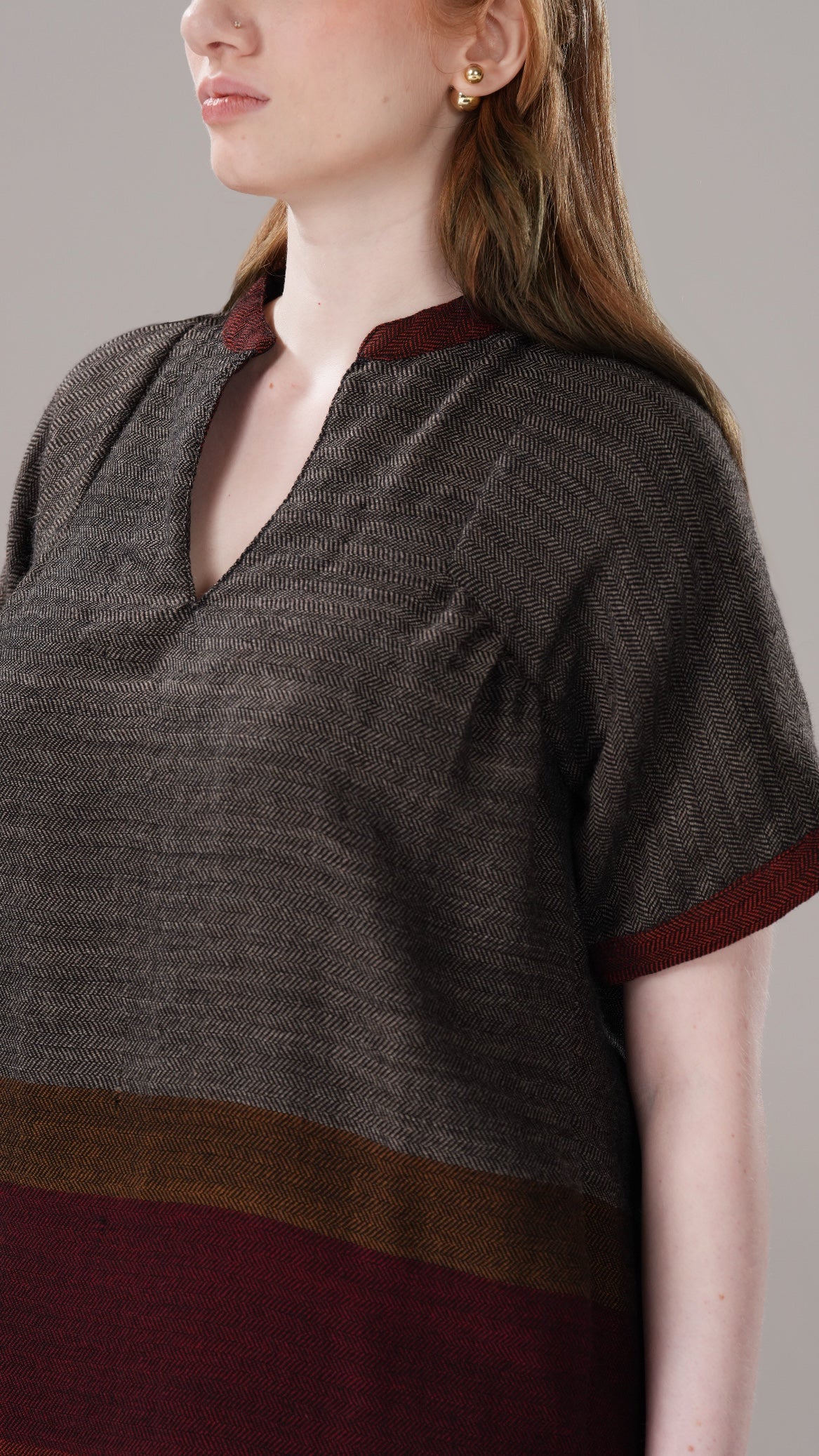 Woman wearing a brown and maroon dress with a plain background
