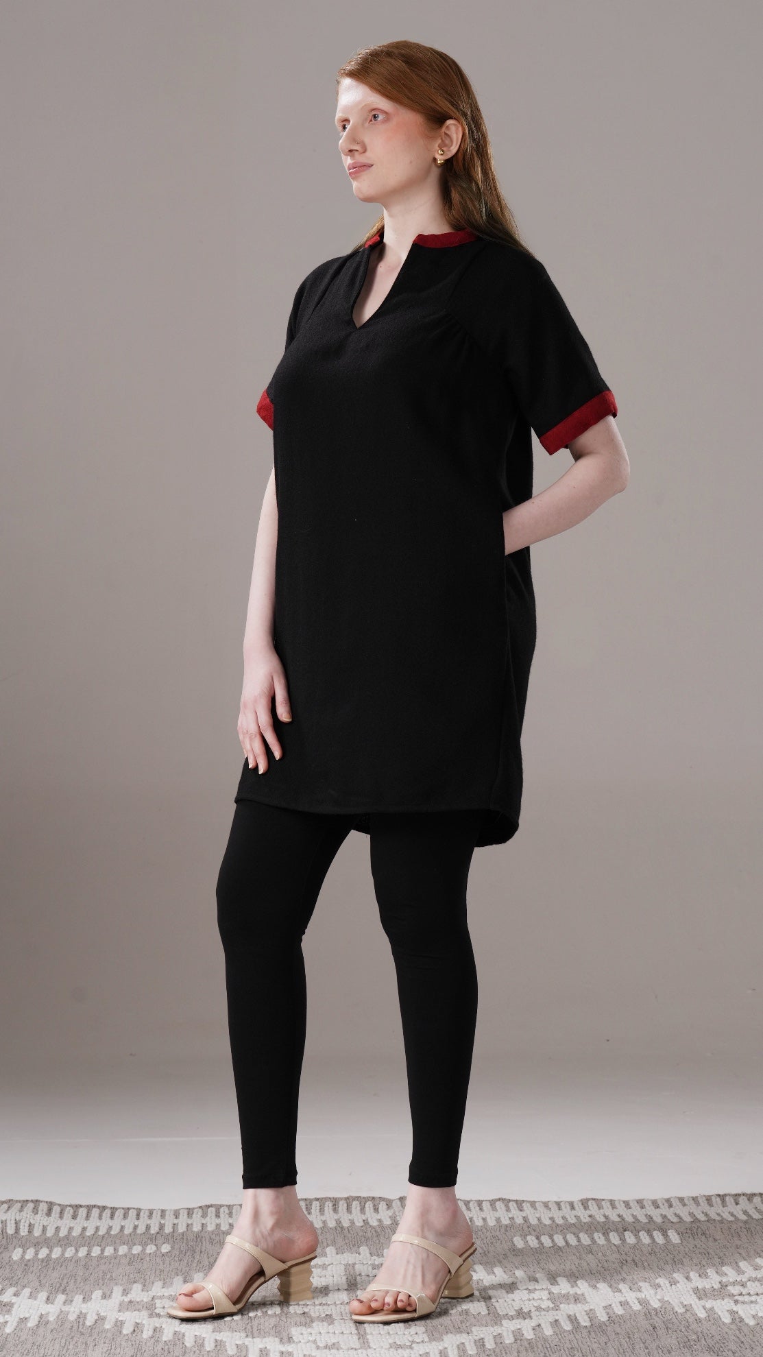 Woman wearing a black dress with red trim against a neutral background