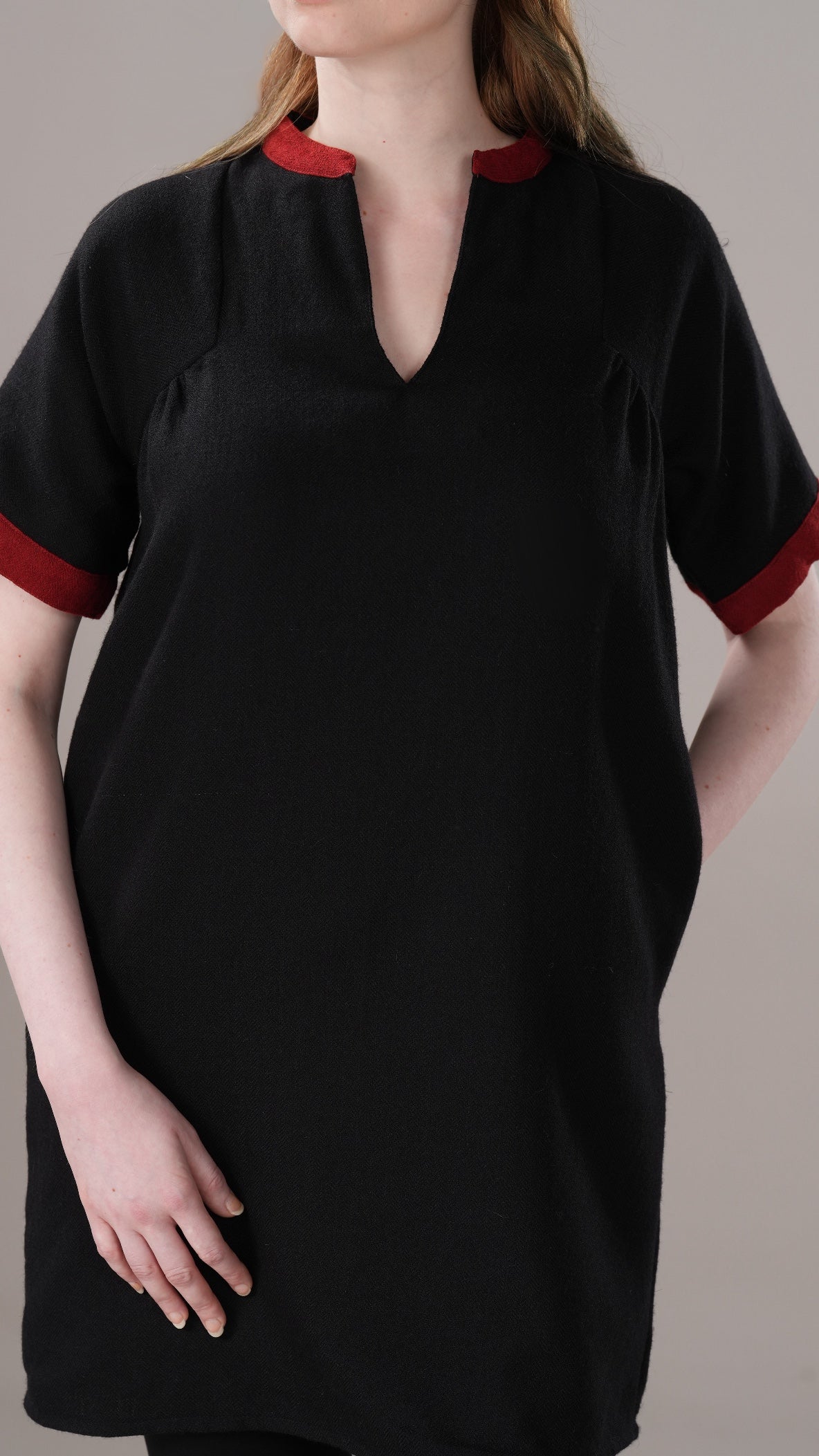 Black dress with red accents worn by a person on a neutral background