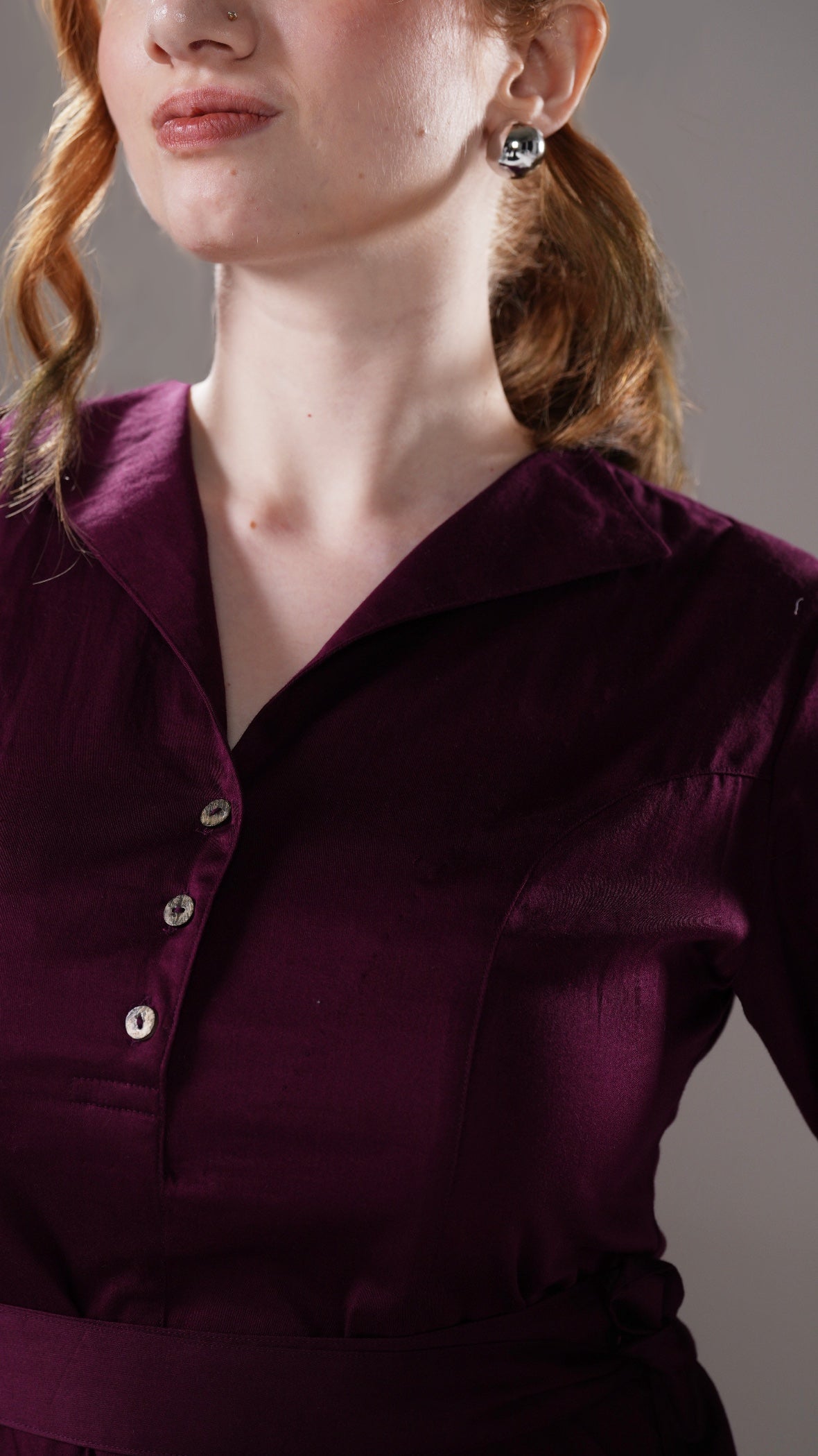 Close-up of a person wearing a dark purple shirt with a neutral background