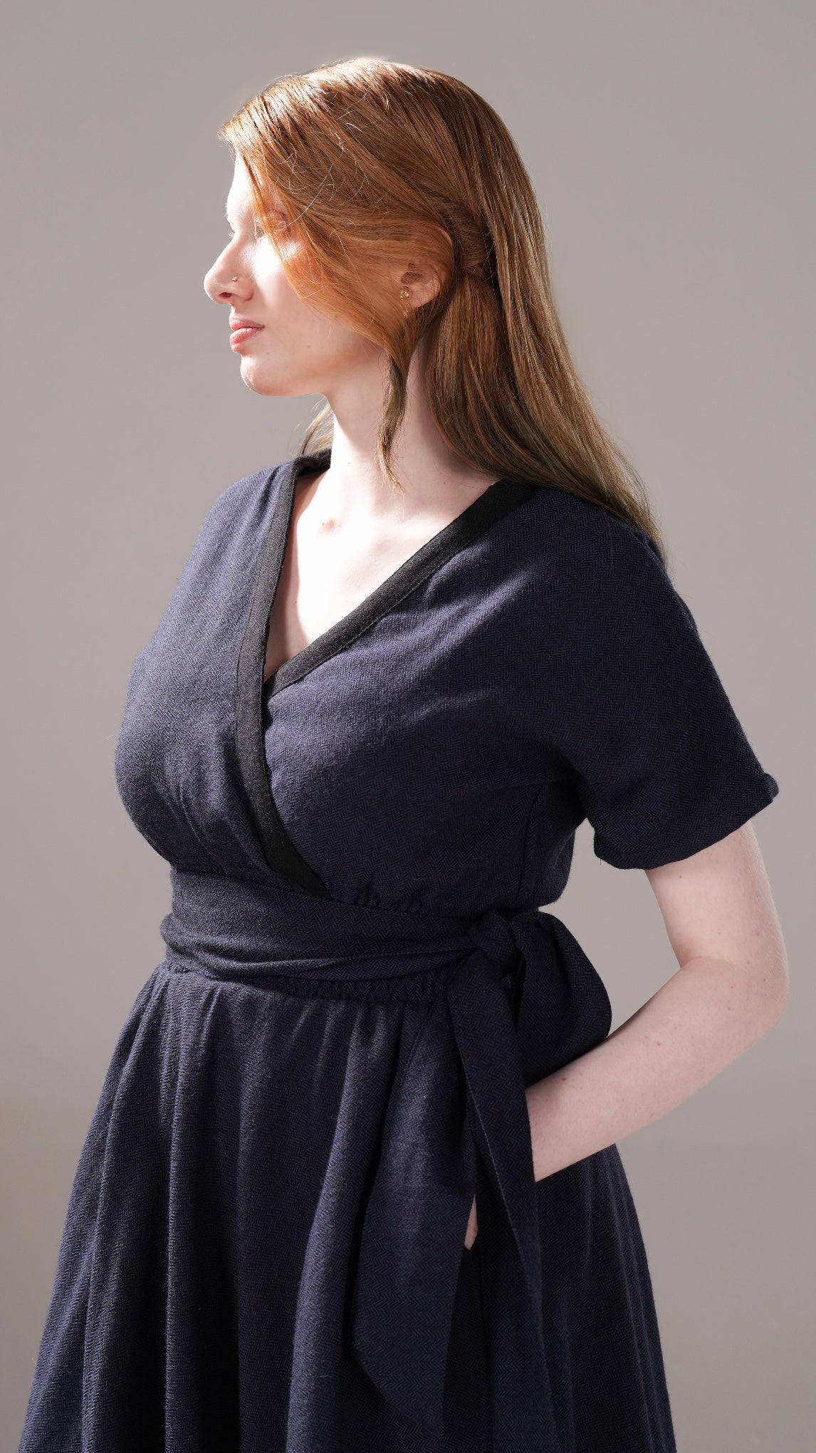 Woman wearing a dark blue dress against a plain background