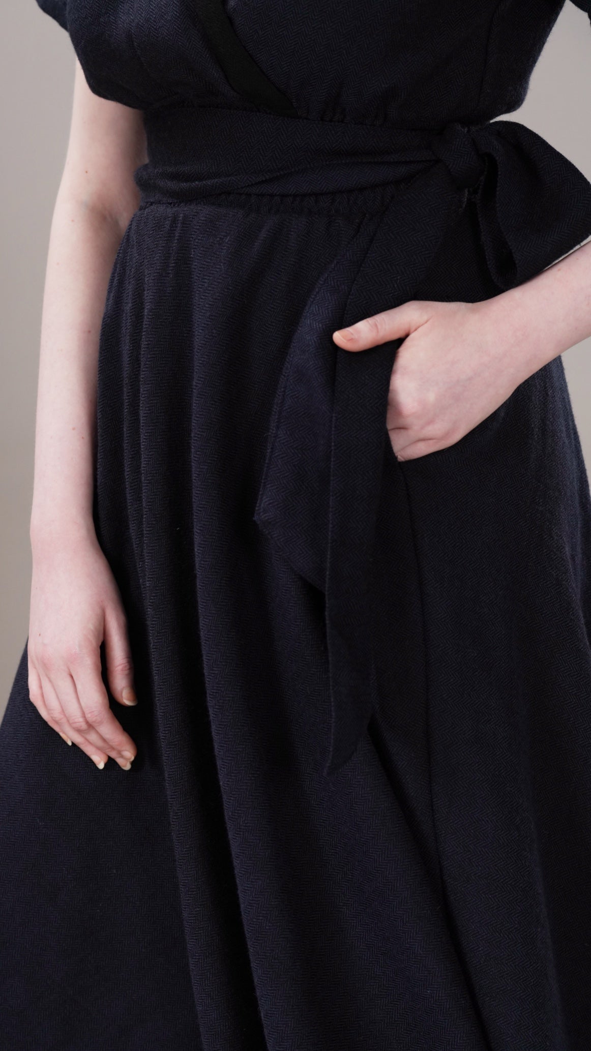 Person wearing a black dress with a plain background