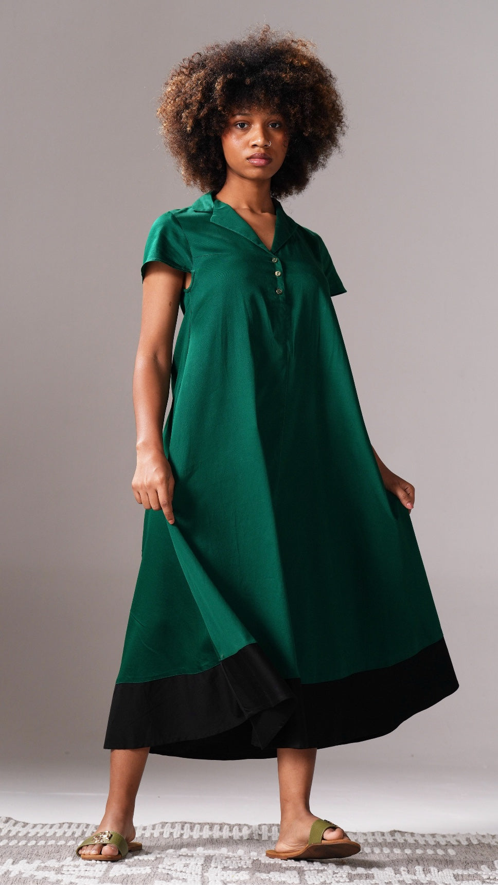 Woman wearing a green dress with a black bottom section on a gray background