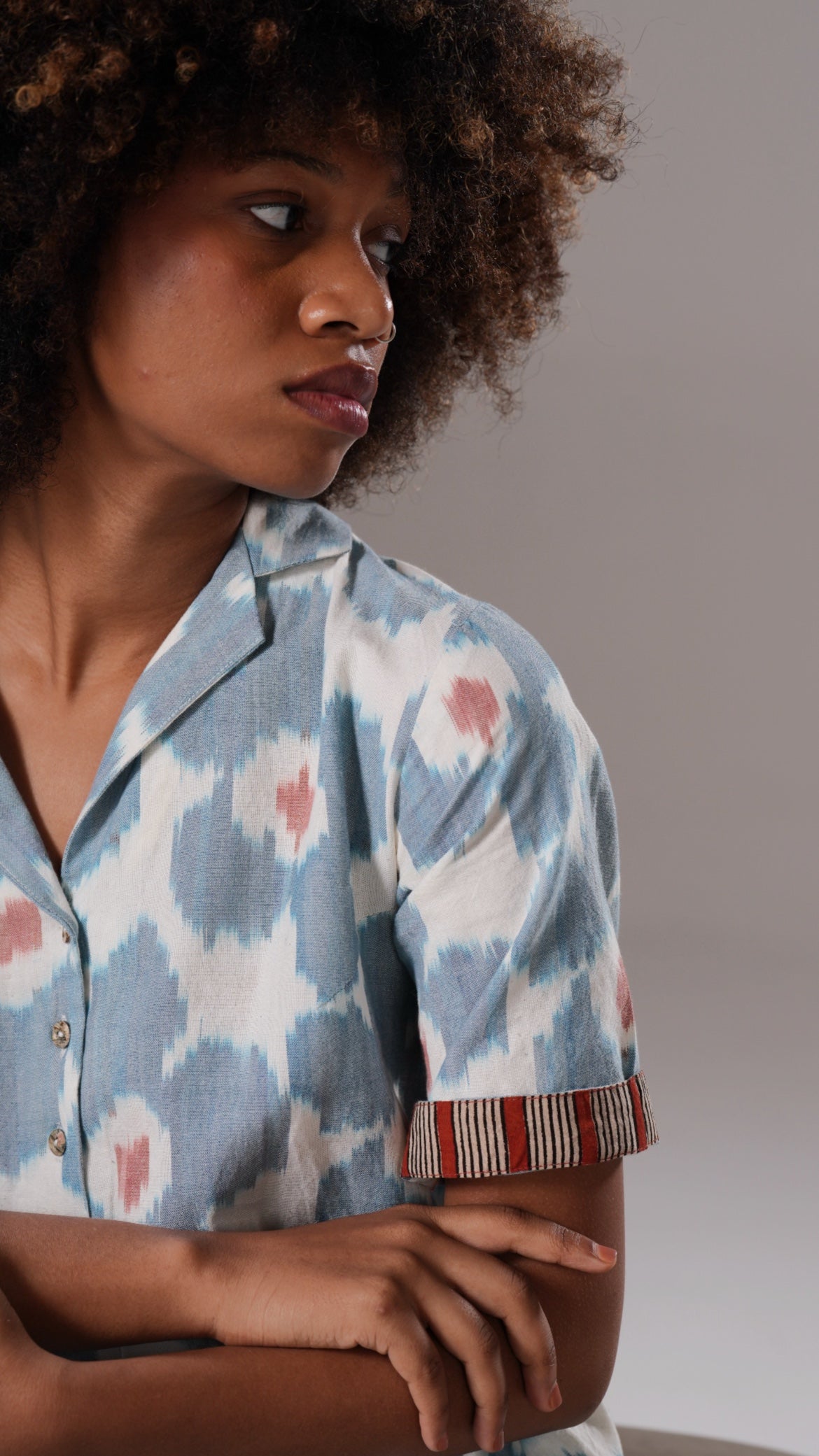 Woman wearing a patterned shirt with a neutral background