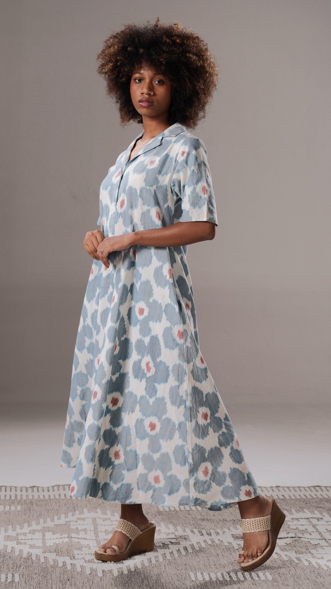 Woman wearing a floral dress standing against a neutral background