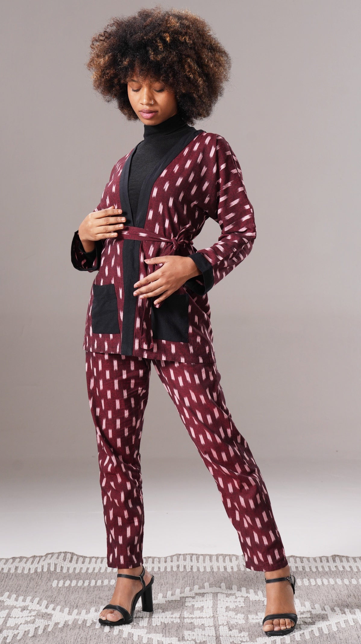Woman wearing a maroon patterned outfit with a black top on a gray background