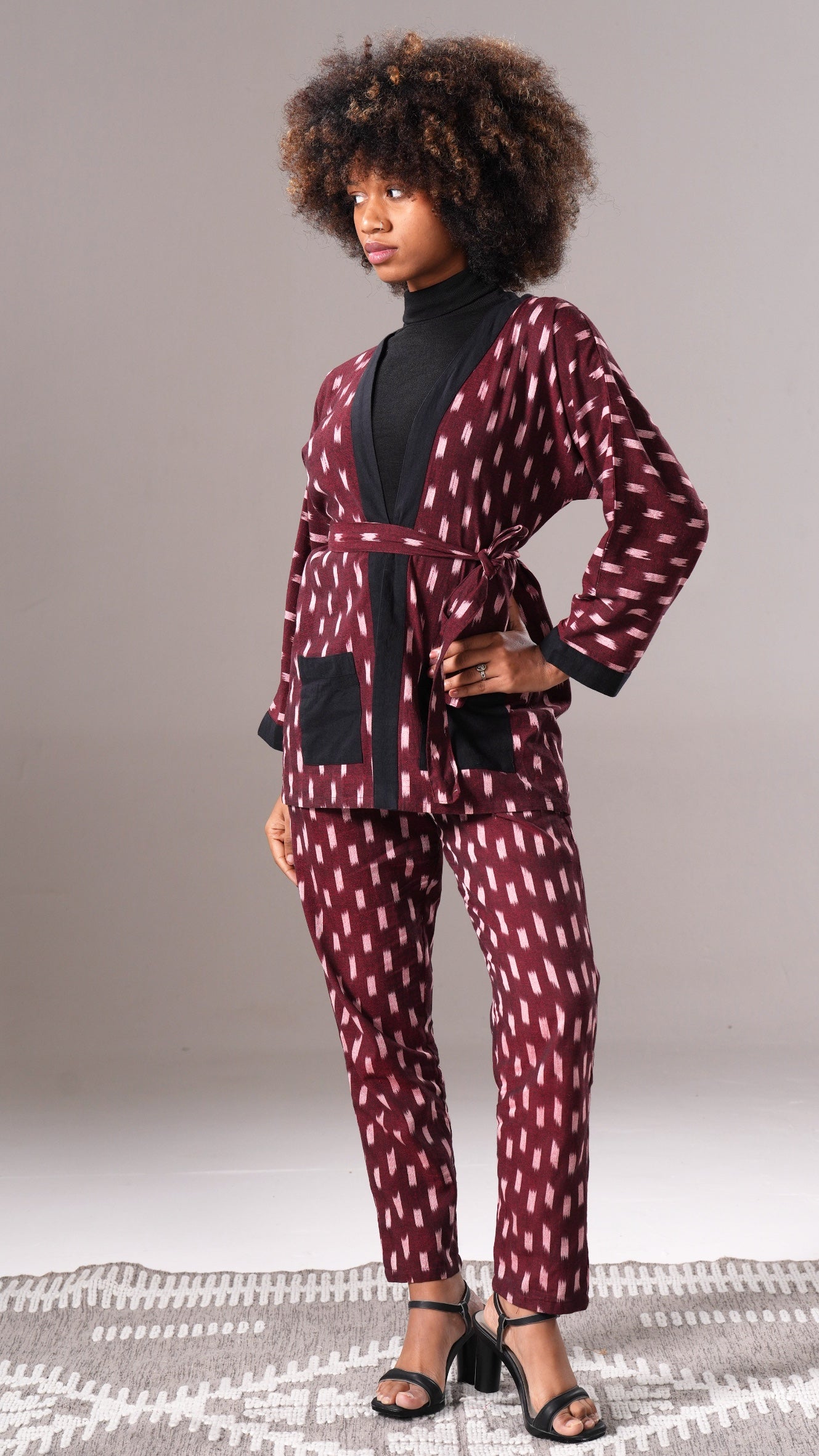 Woman wearing a patterned outfit with a belt against a neutral background