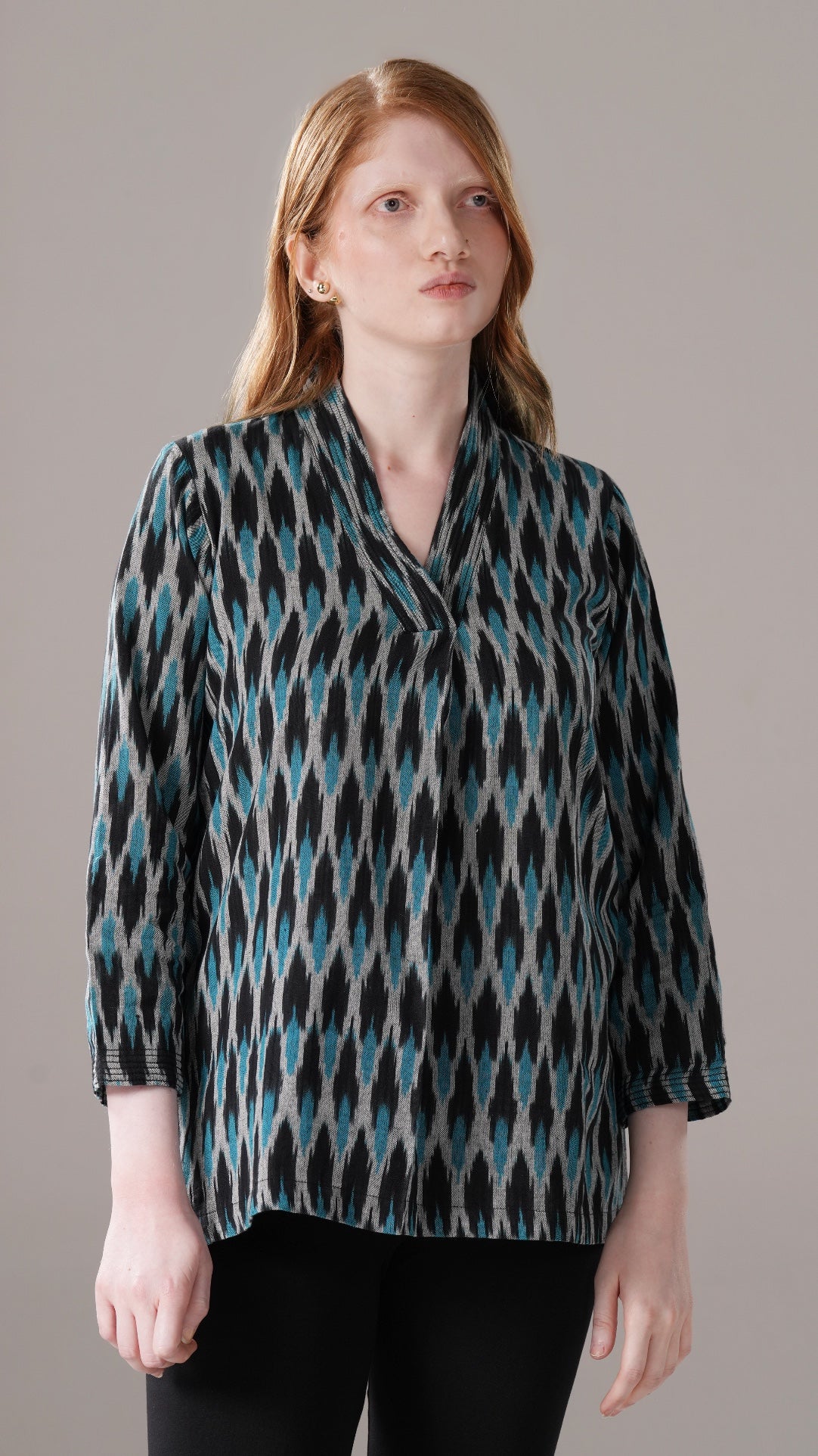 Woman wearing a patterned blouse against a gray background