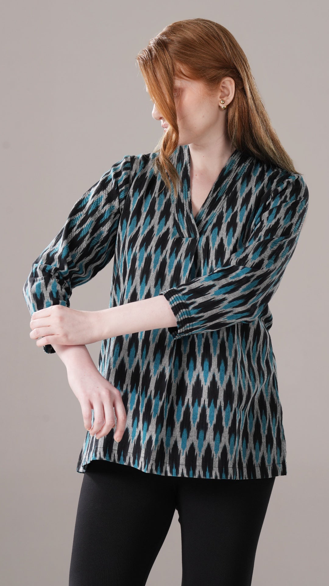 Woman wearing a patterned blouse against a plain background
