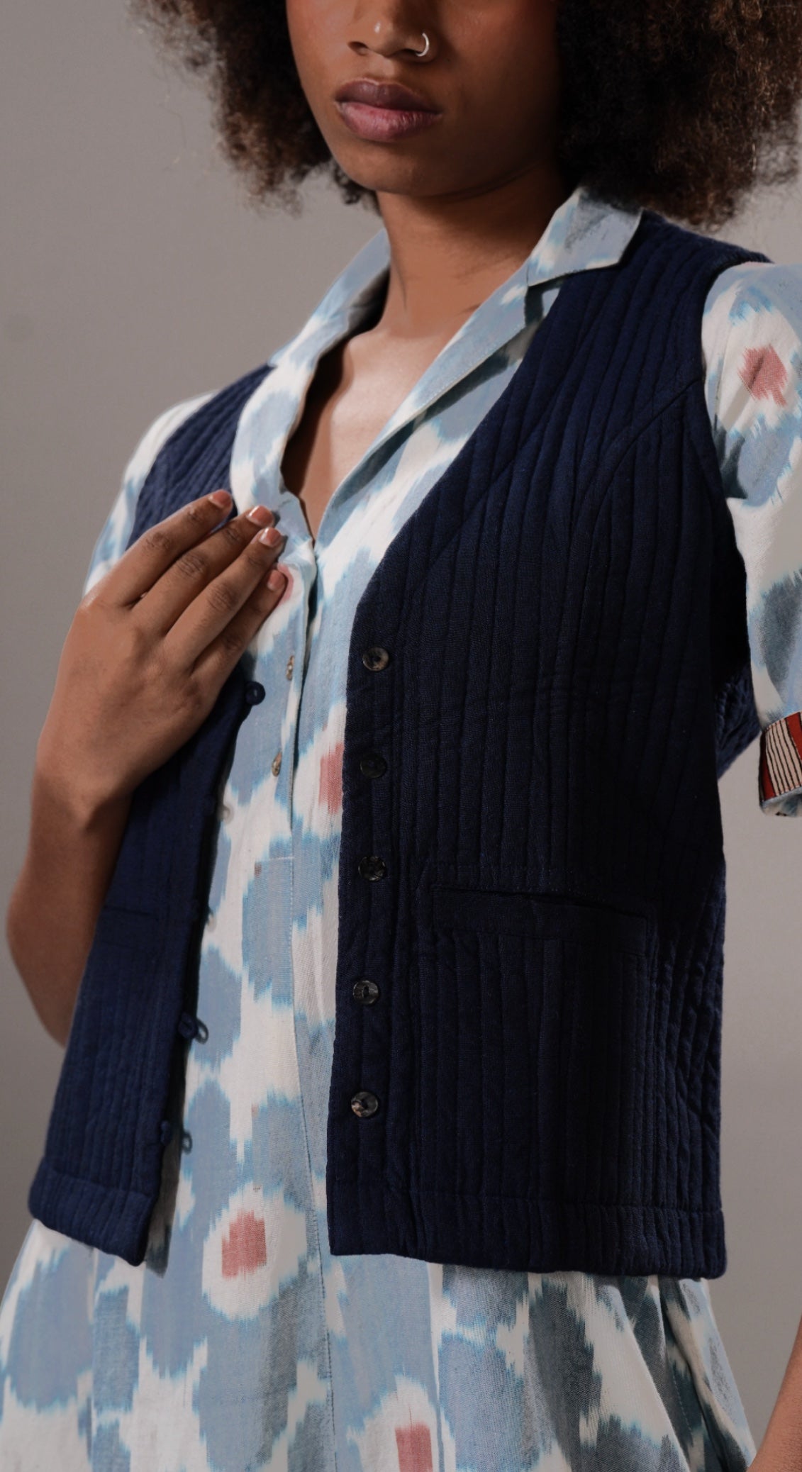 Woman wearing a navy cardigan over a floral dress with a neutral background