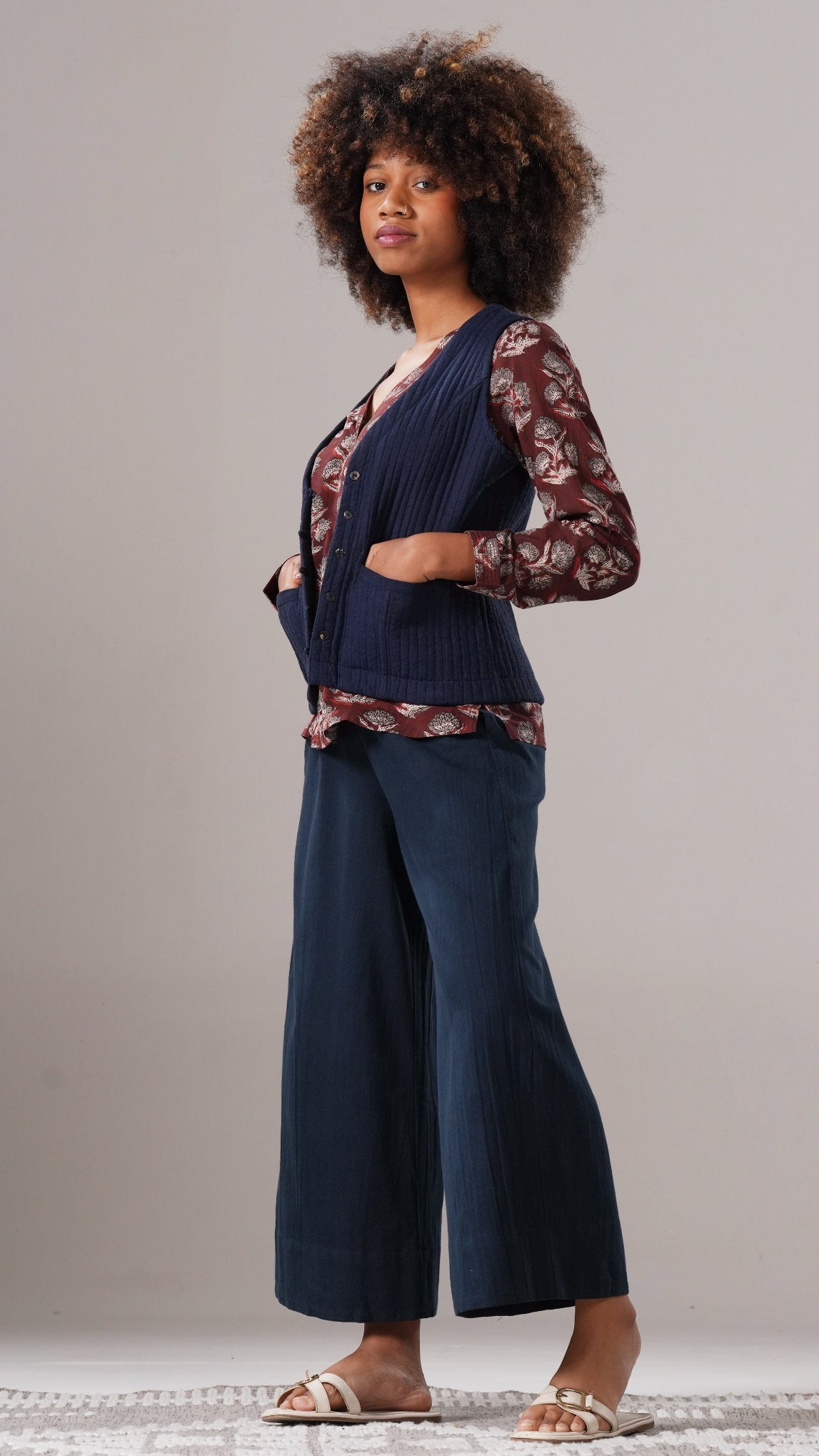 Woman wearing a navy cardigan over a patterned top with wide-leg pants on a neutral background