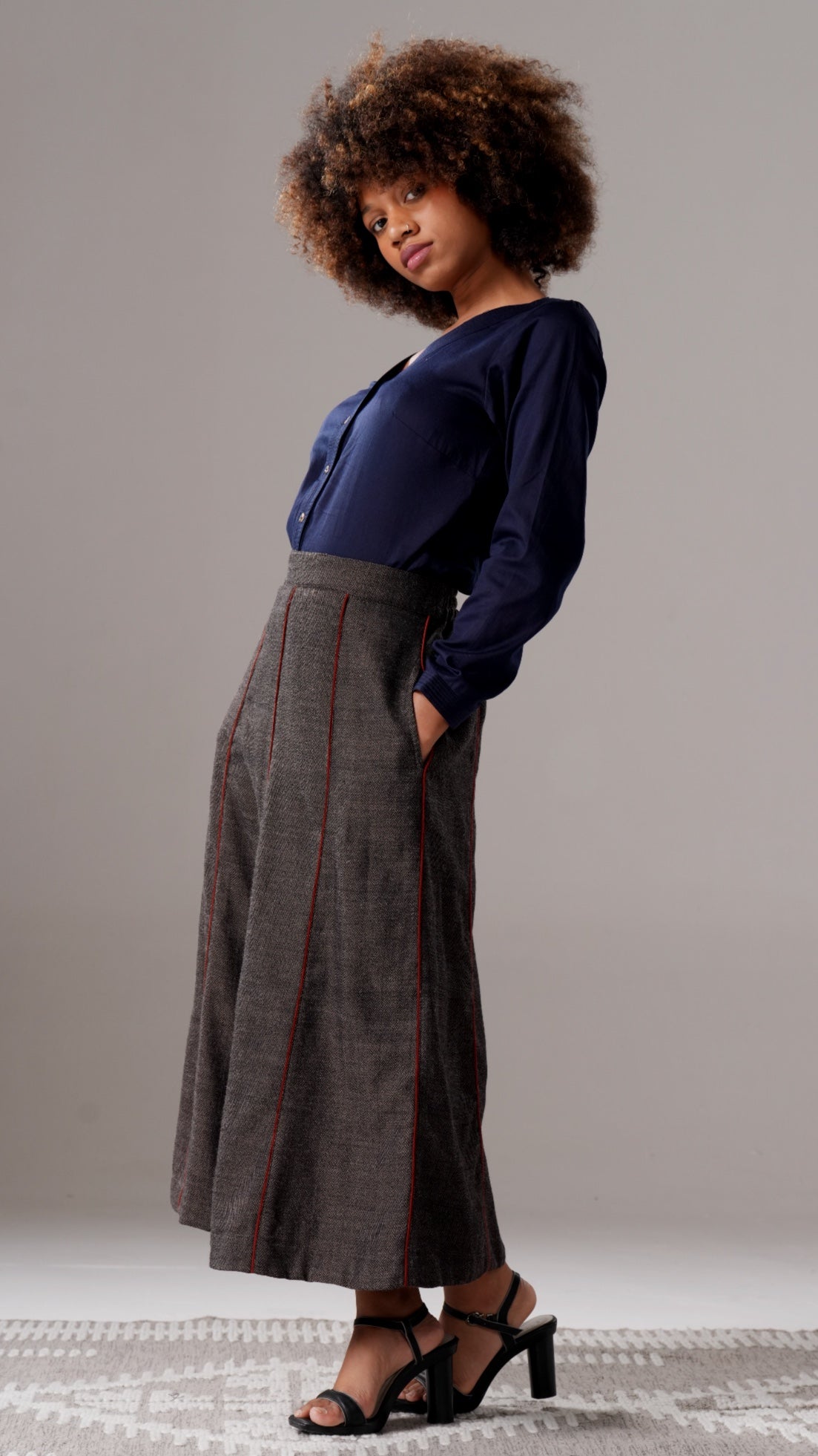 Woman wearing a blue shirt and gray skirt against a neutral background