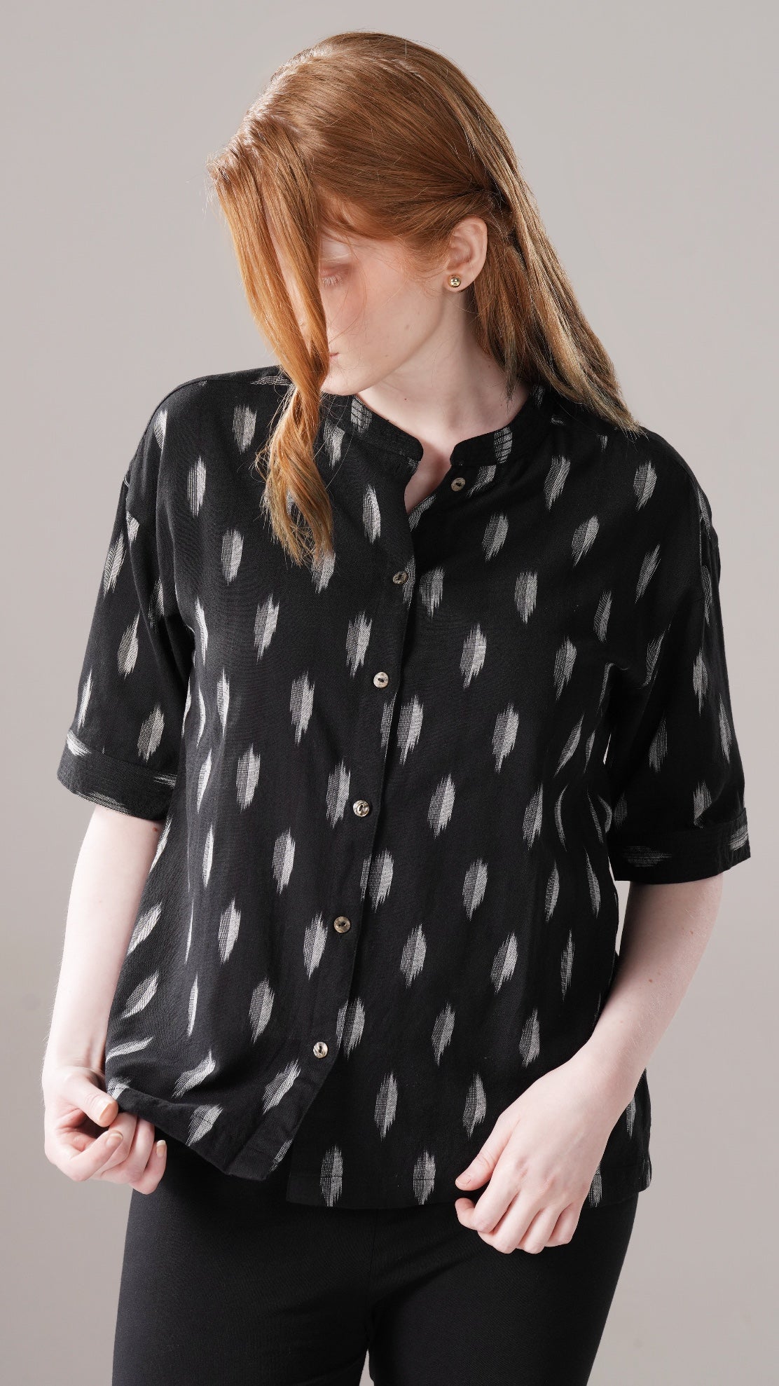 Person wearing a black patterned shirt against a gray background