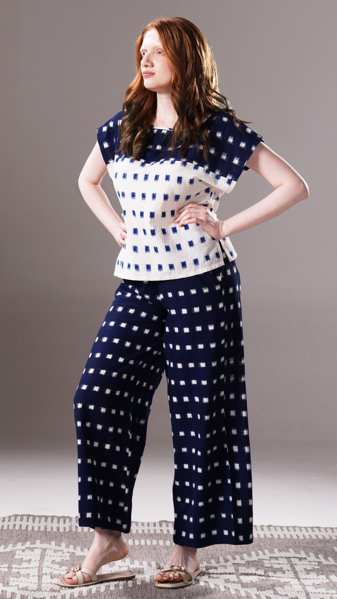 Woman wearing a navy and white patterned outfit on a plain background
