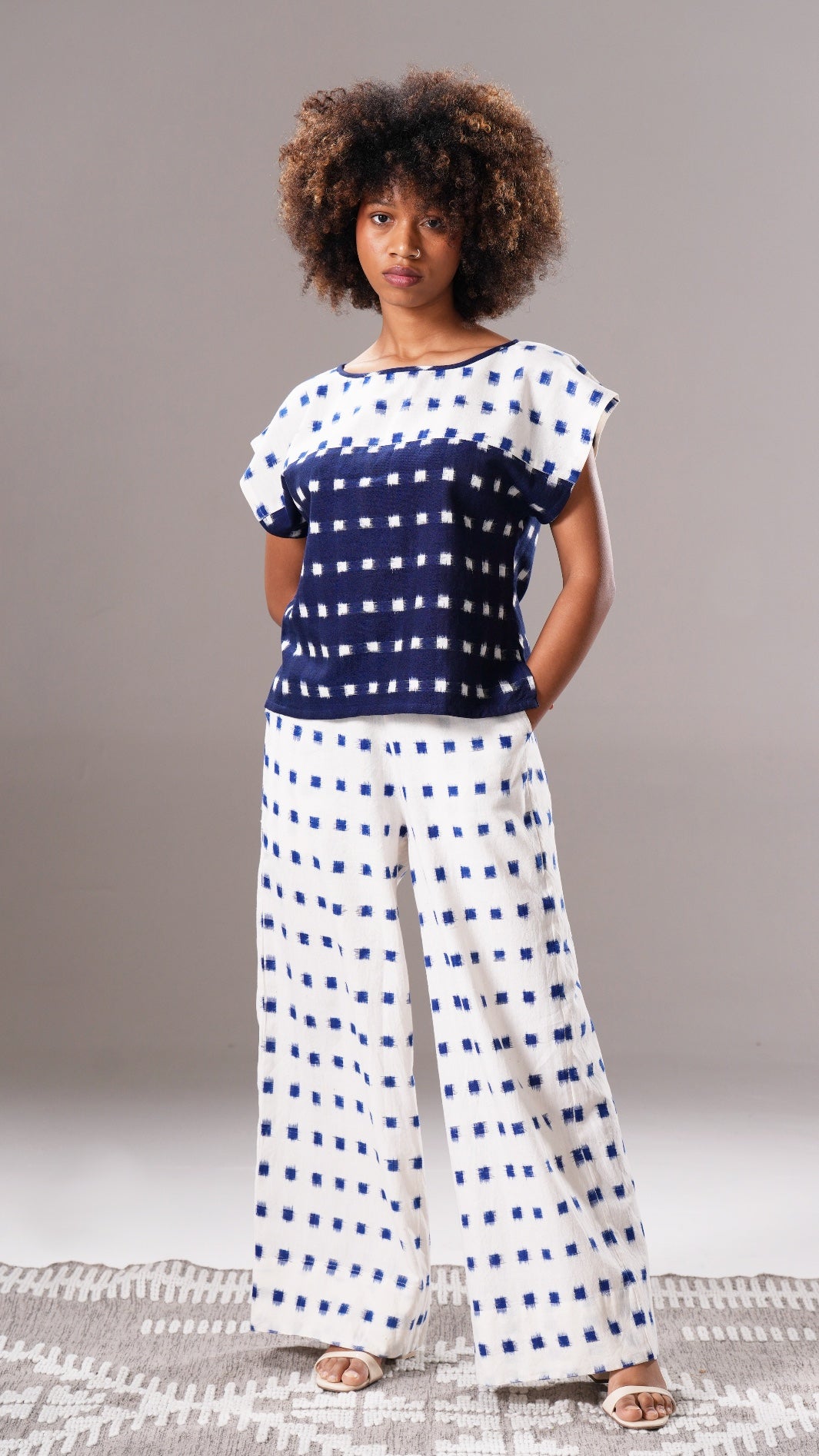 Woman wearing a navy and white patterned outfit on a plain background