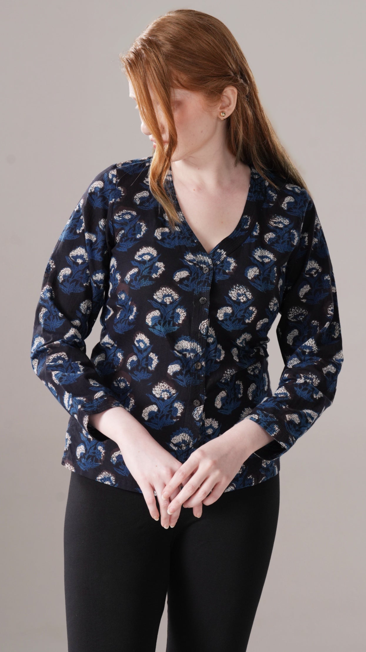 Woman wearing a dark blue floral patterned blouse against a plain background