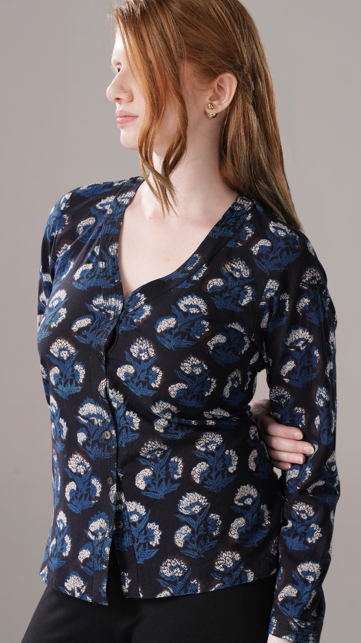 Woman wearing a blue patterned blouse against a gray background