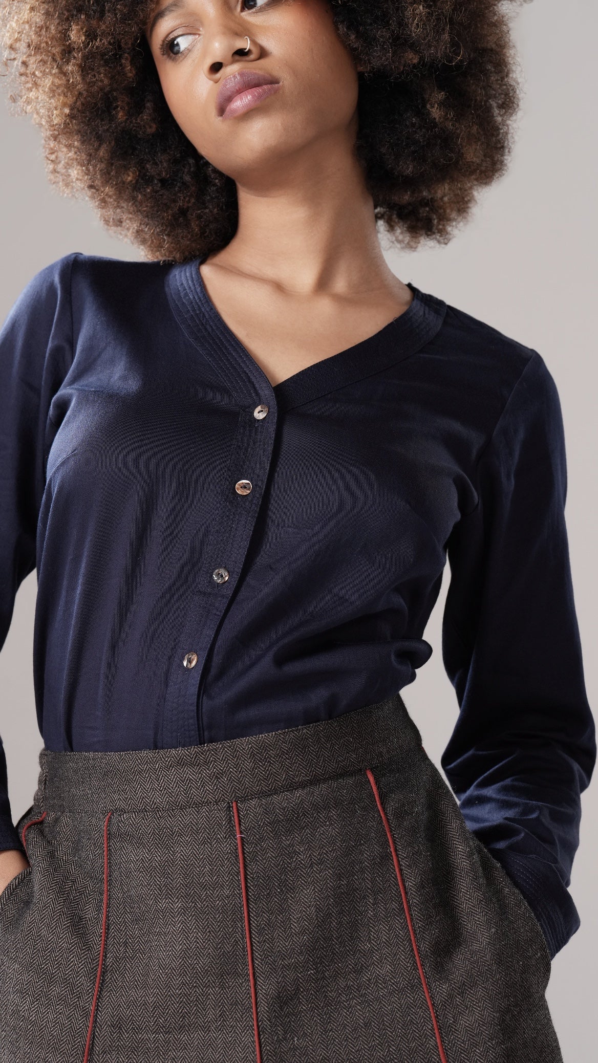 Woman wearing a navy cardigan and gray pants against a neutral background