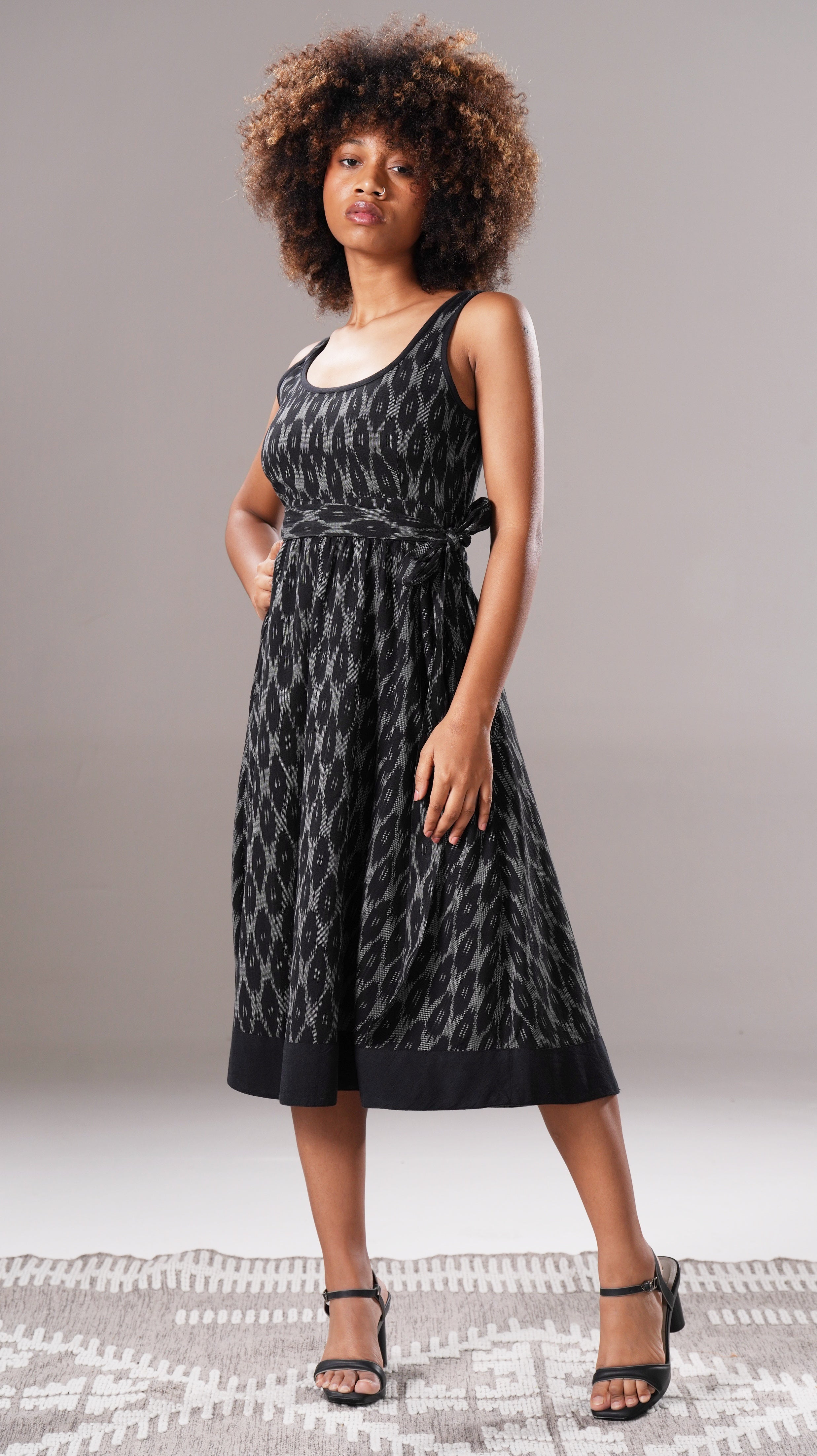 Woman wearing a black patterned dress on a gray background
