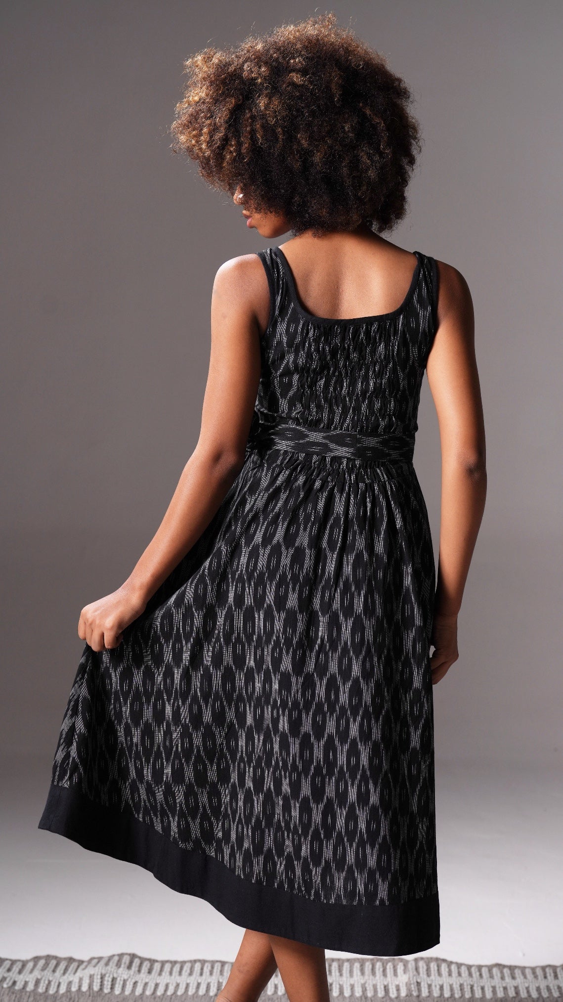 Woman wearing a black patterned dress against a gray background