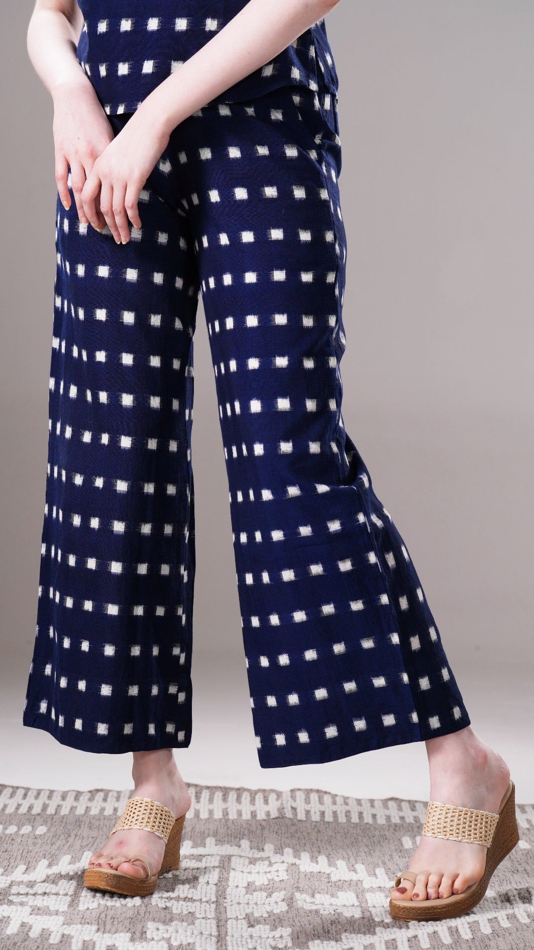 Navy blue pants with white square pattern worn by a person on a neutral background