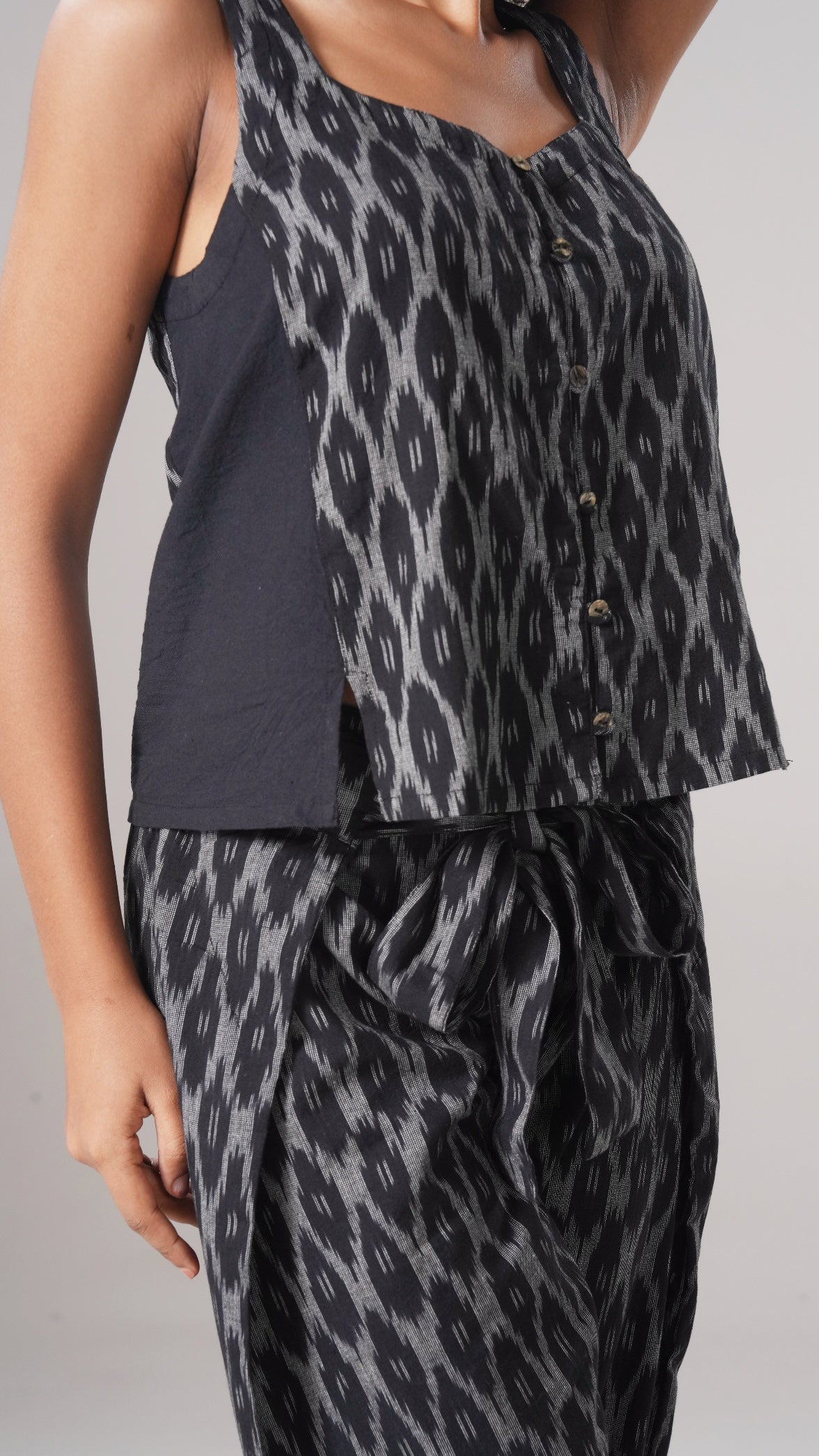 Person wearing a black and gray patterned outfit on a plain background