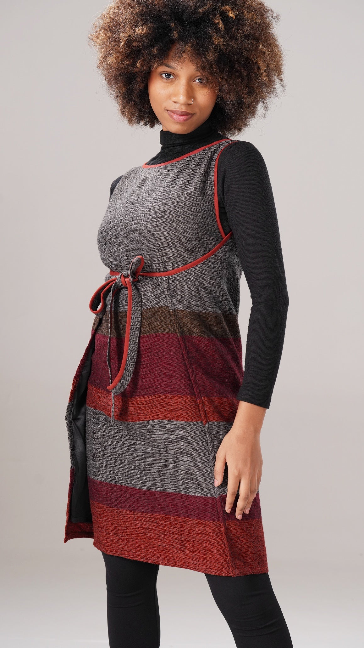 Woman wearing a gray and red striped dress with a plain background