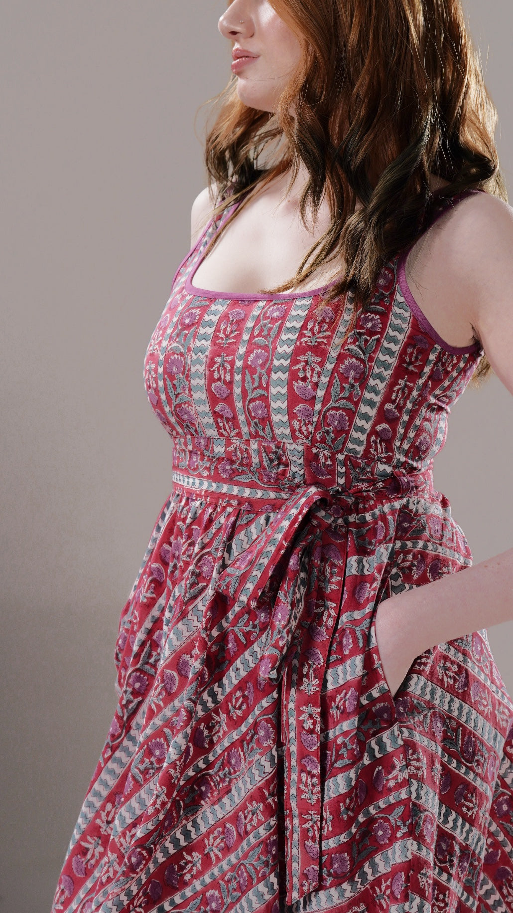 Woman wearing a red patterned dress against a plain background