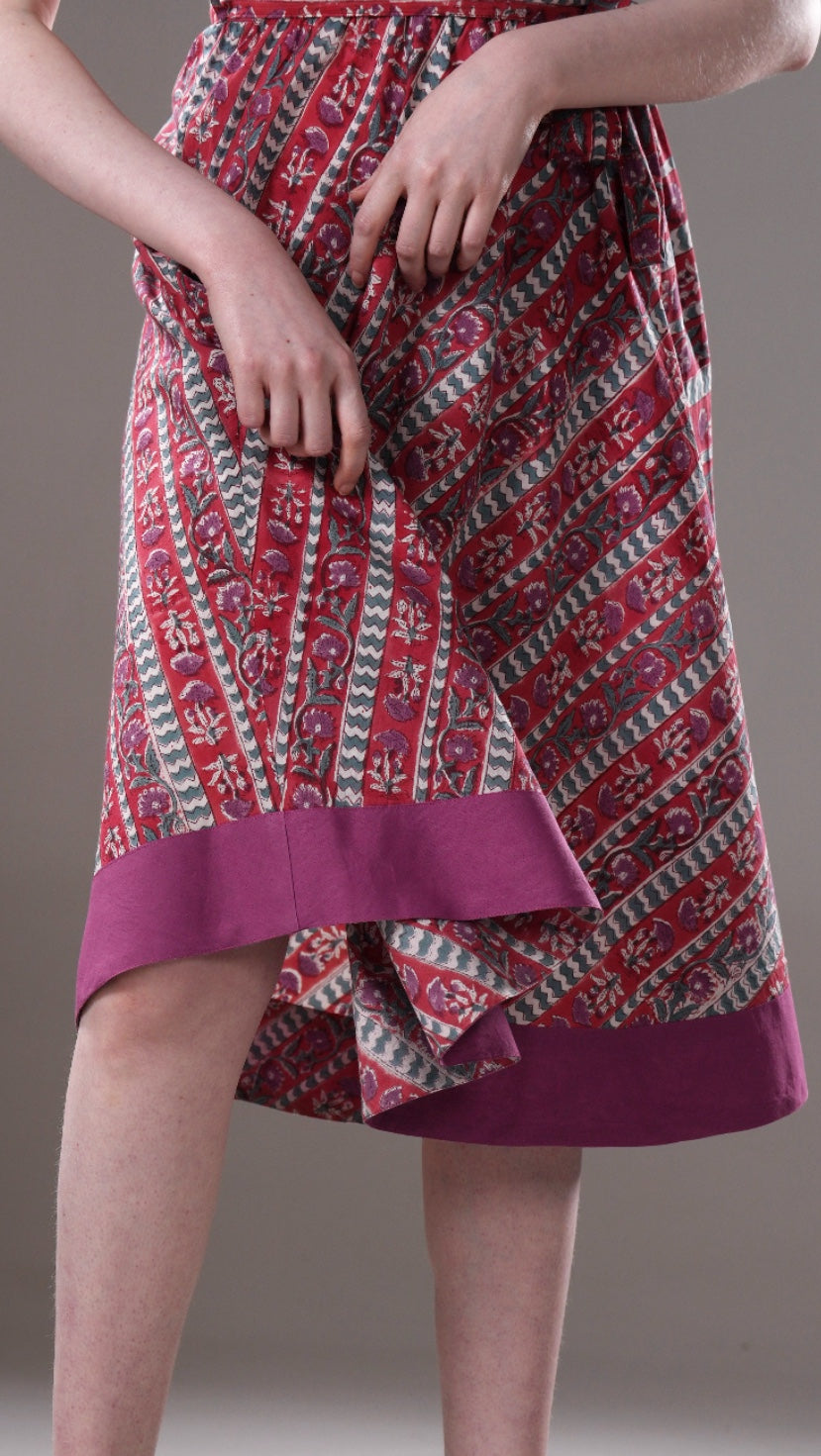 Red and white patterned dress with a purple hem on a neutral background