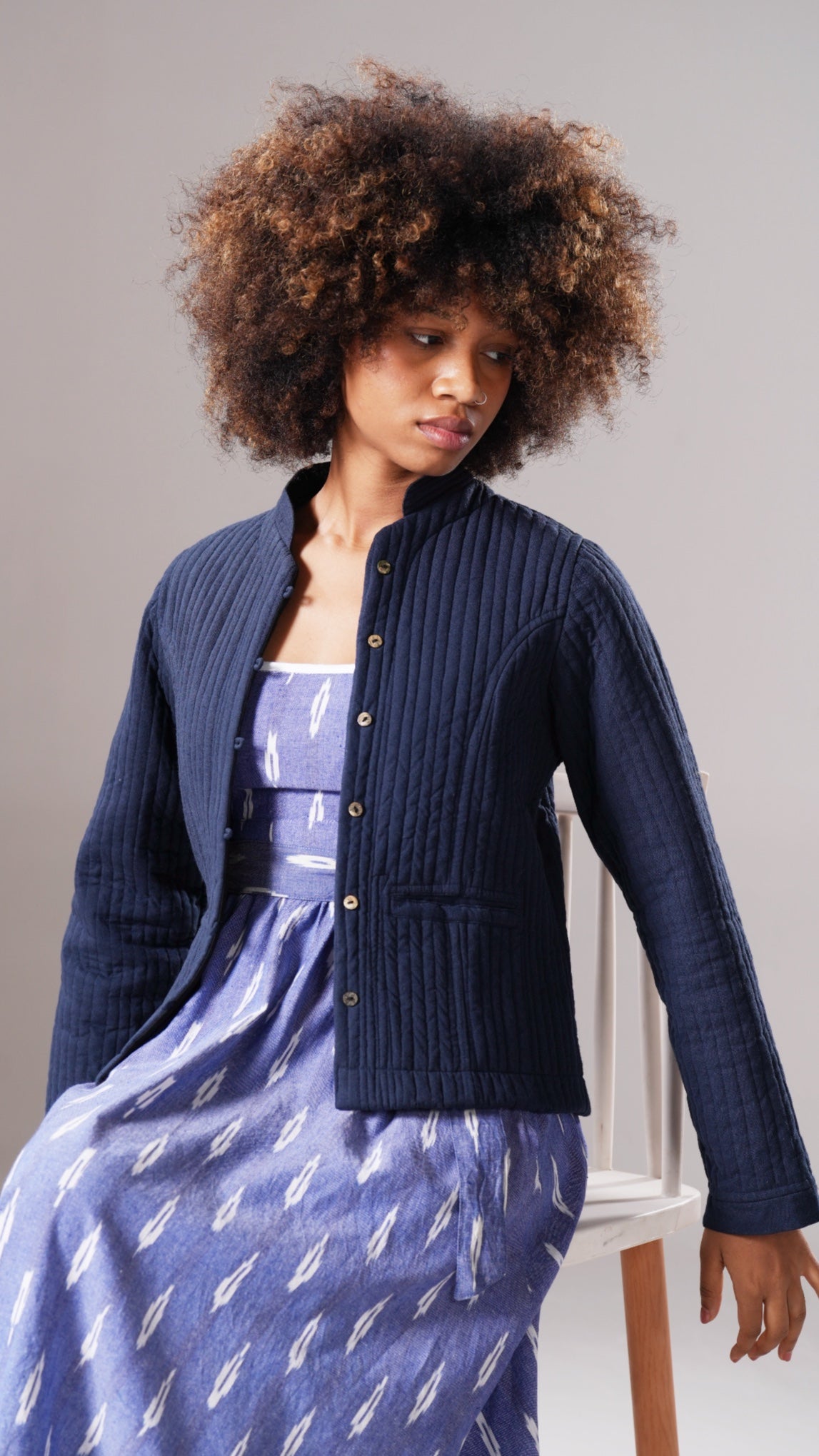 Woman wearing a navy blue cardigan over a patterned dress against a plain background