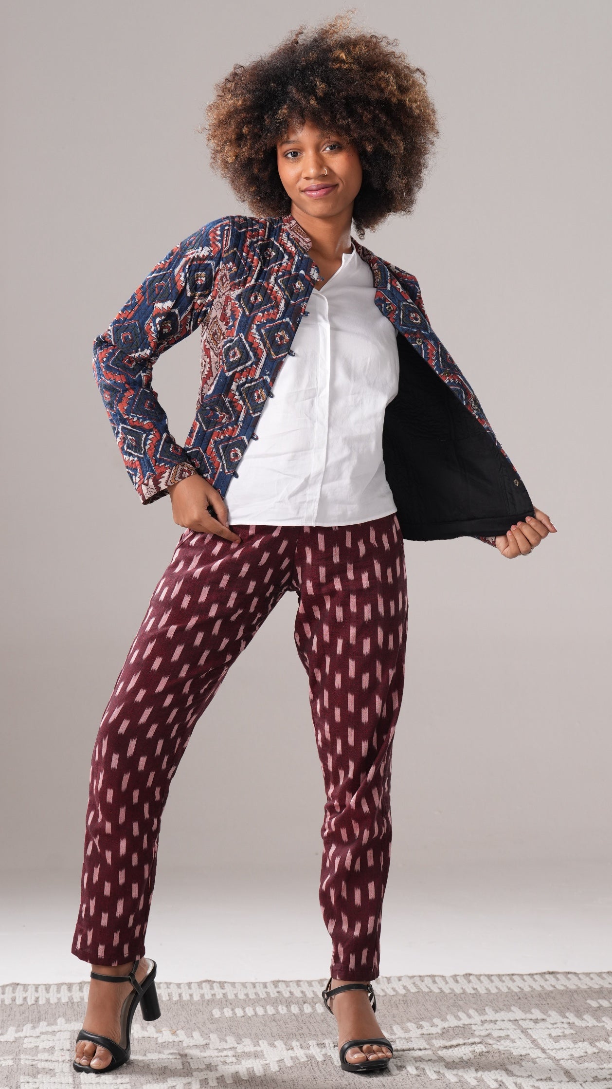 Woman wearing a patterned jacket and pants on a plain background