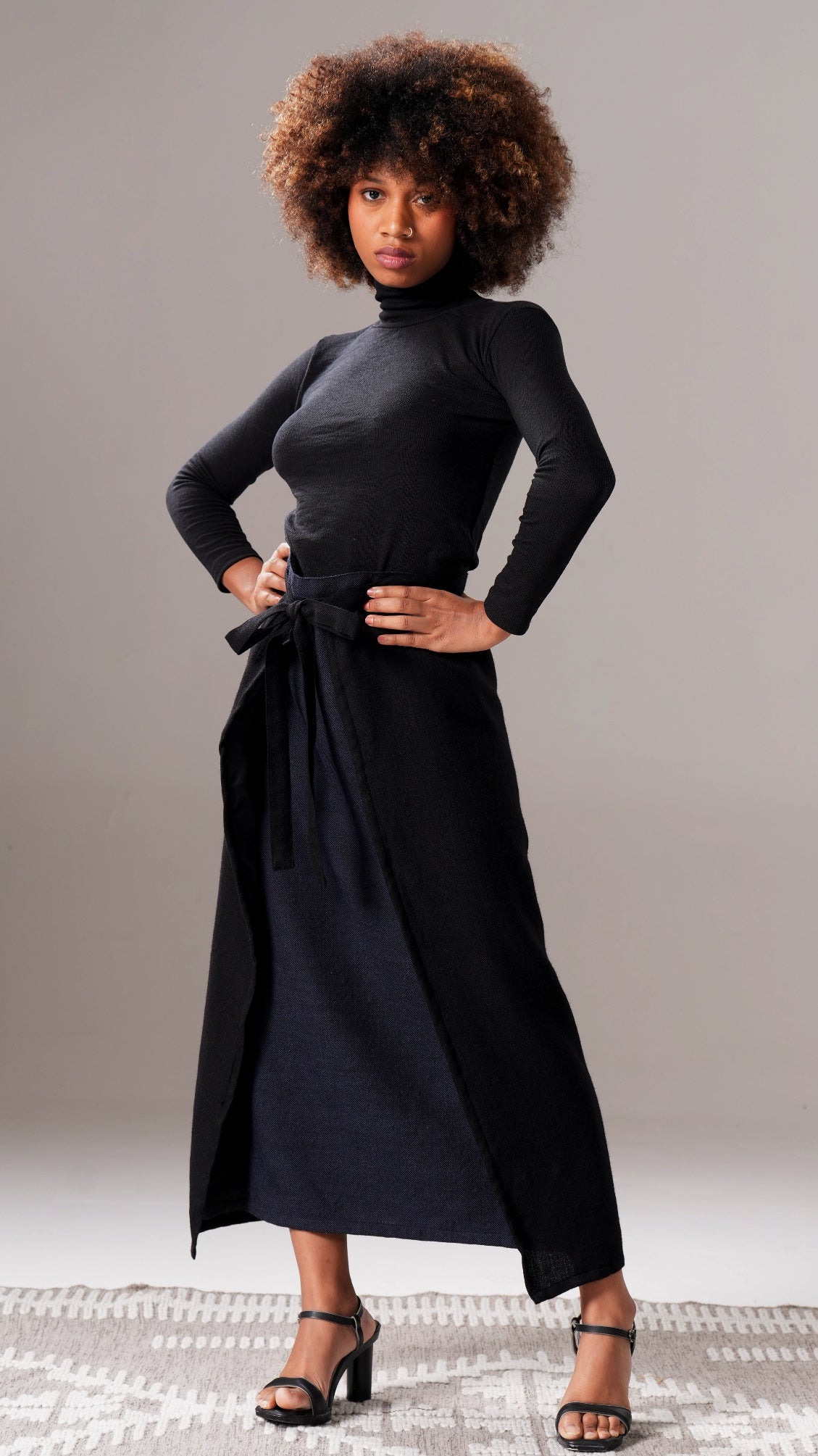 Woman wearing a black turtleneck dress against a neutral background